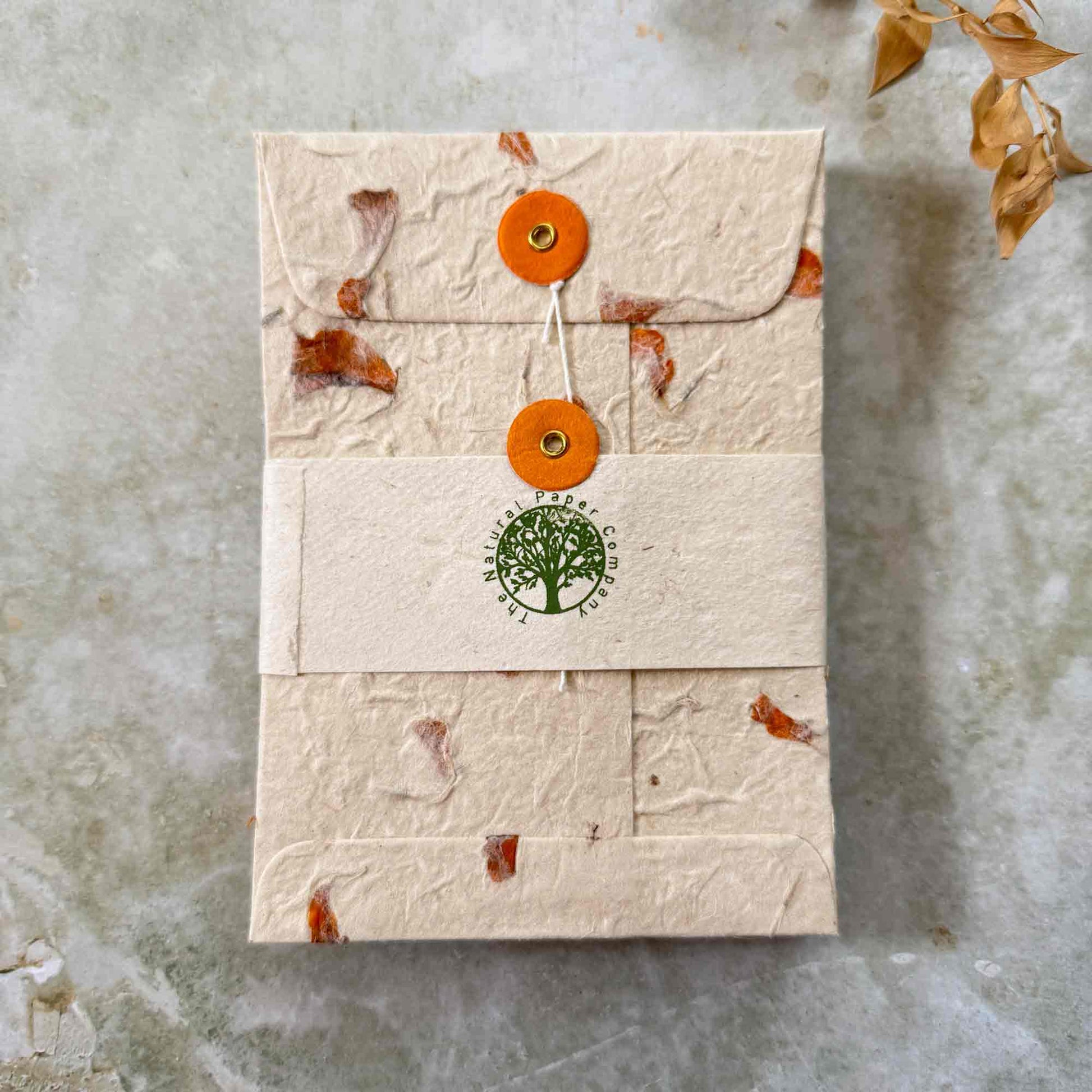 Envelope set wrapped in branded paper band, crafted from lokta paper with pressed marigold petals. Tree-free, sustainable eco-friendly stationery by The Natural Paper Company...
