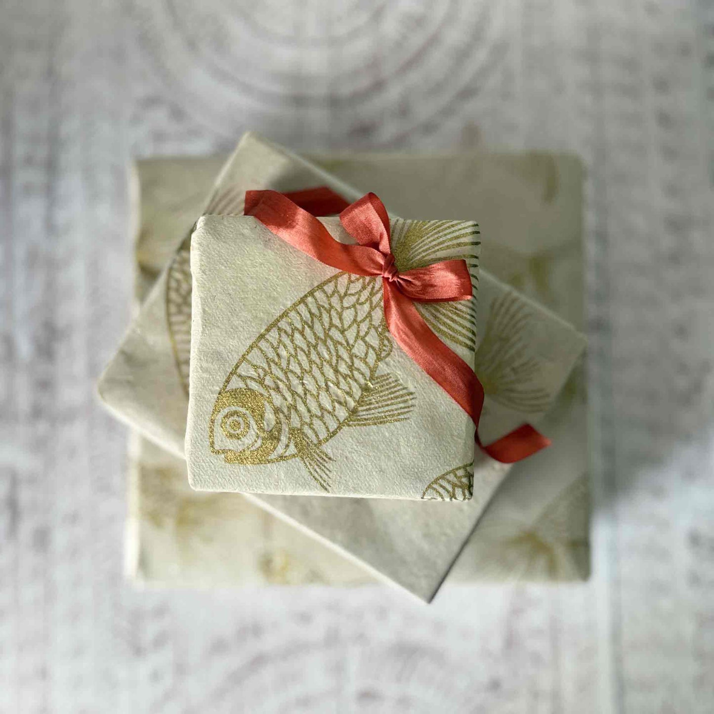Top-down view of stacked gift boxes wrapped in sustainable Lokta paper with koi fish pattern