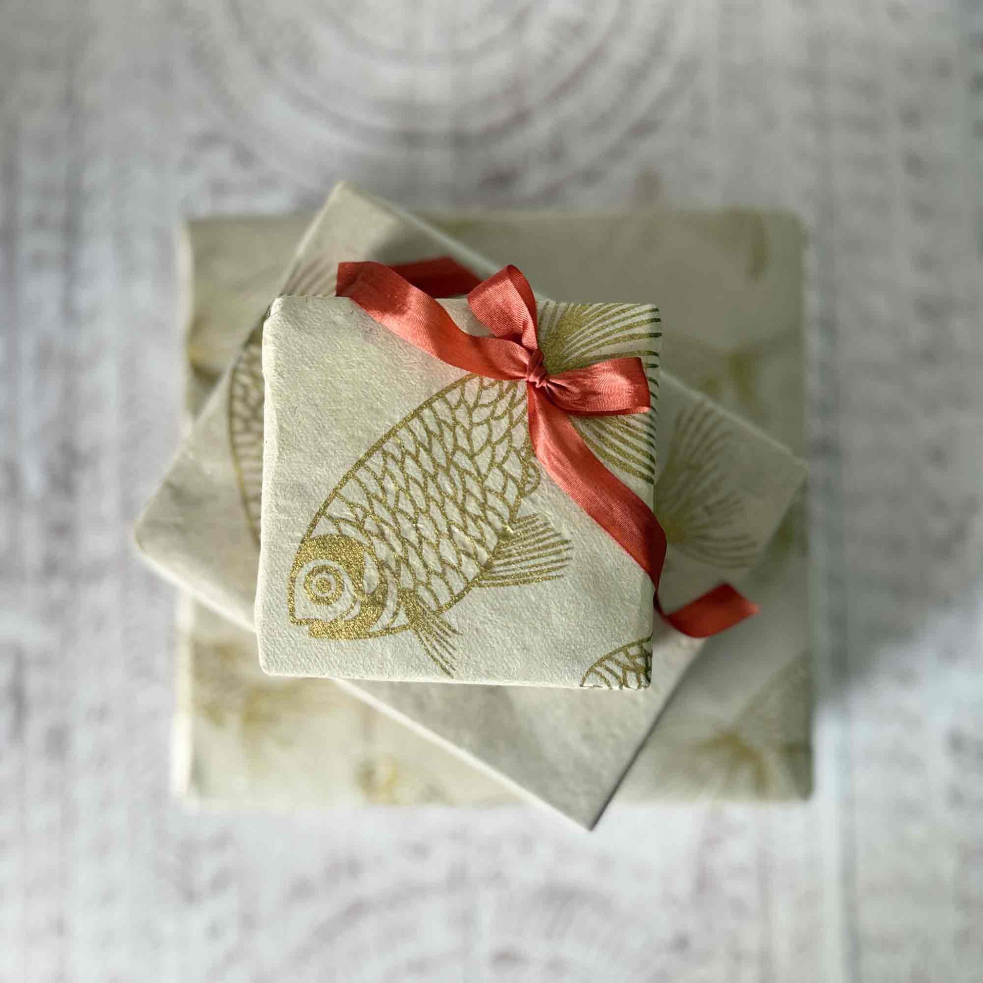 Top-down view of stacked gift boxes wrapped in sustainable Lokta paper with koi fish pattern