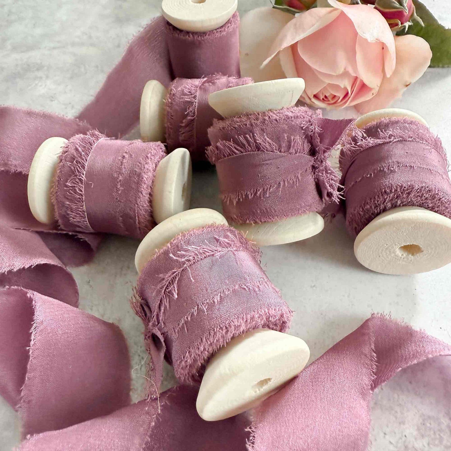 Silk ribbon on a wooden reel.  Mauve colour silk with a raw edge