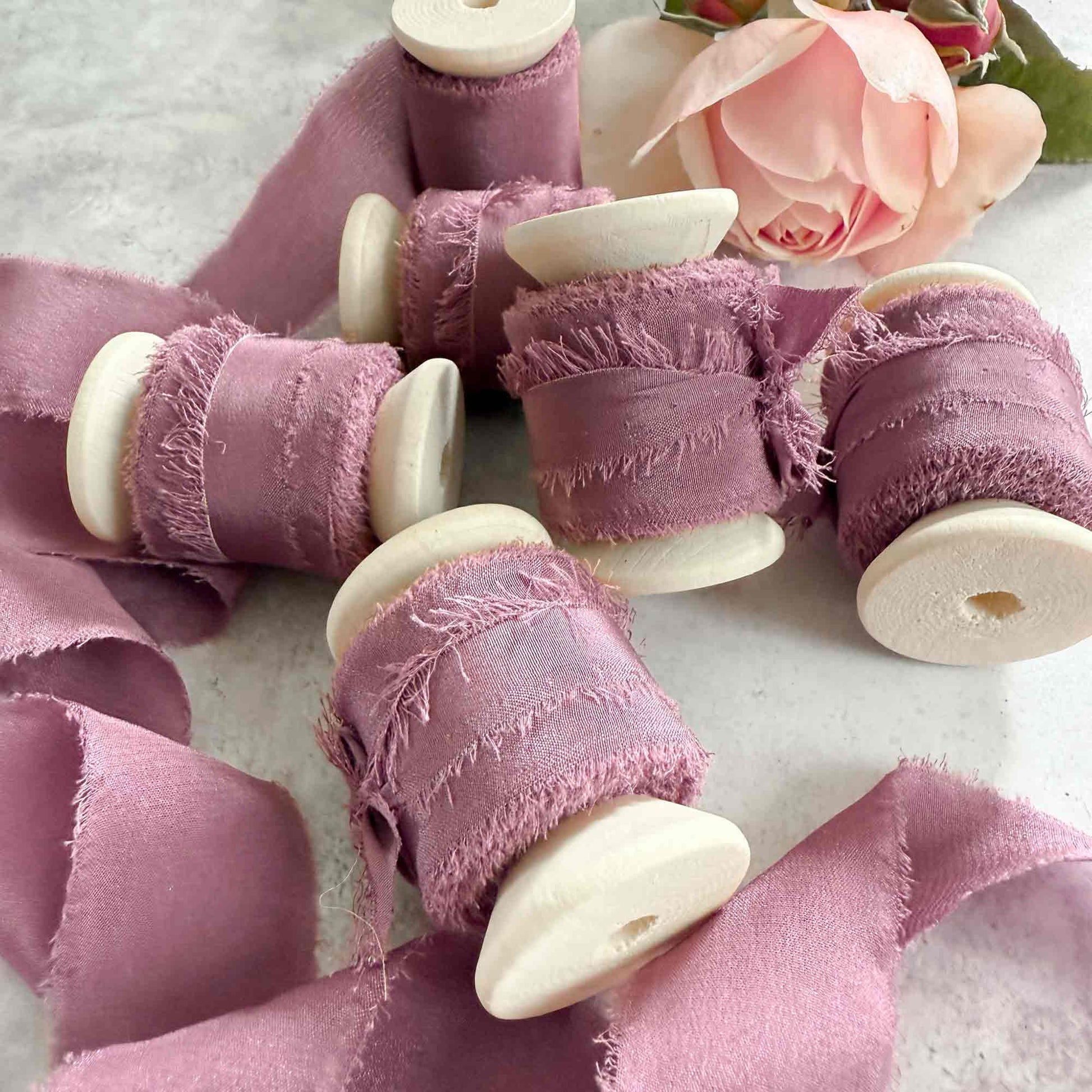 Silk ribbon on a wooden reel.  Mauve colour silk with a raw edge