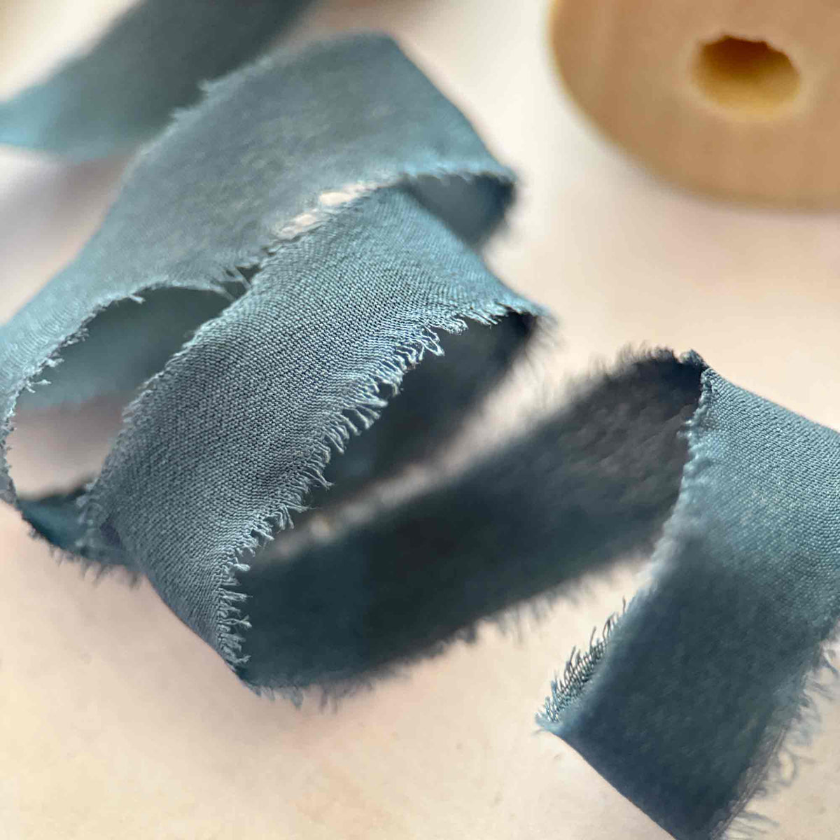 Close-up of Navy 10mm raw edge Habotai silk ribbon with softly frayed edges