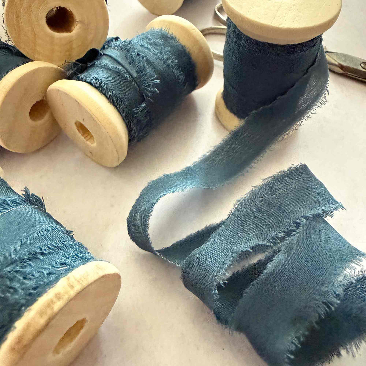Navy 10mm Habotai silk ribbon with frayed edges wound around wooden reels