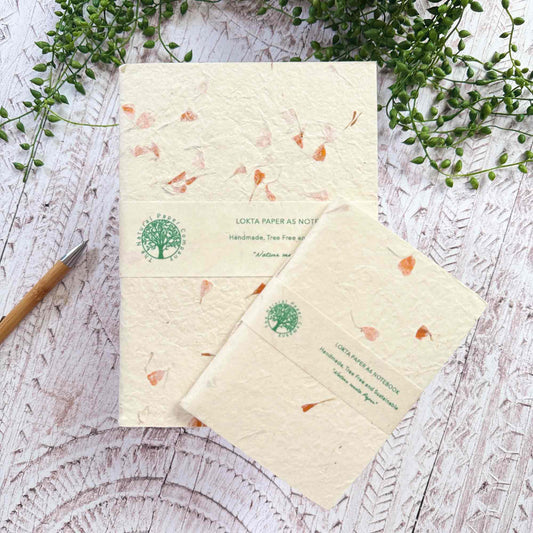 Marigold Lokta notebooks in A5 and A6 sizes, showing branded paper band, hand‑stitched binding, and scattered orange flower petal design