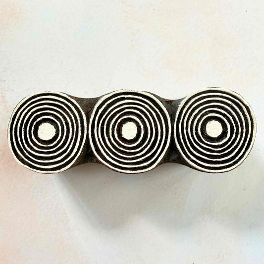 Hand-carved Orbits Indian wood block stamp — three concentric circles in a row face-on view on soft pale background, traditional printing block close-up
