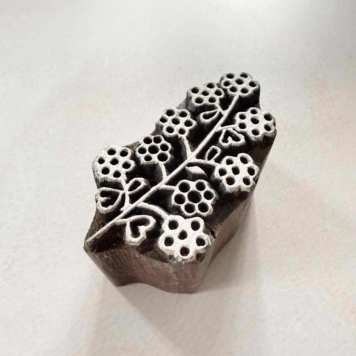Angled view of Padma floral wooden printing block with flowers, leaves and branching stem