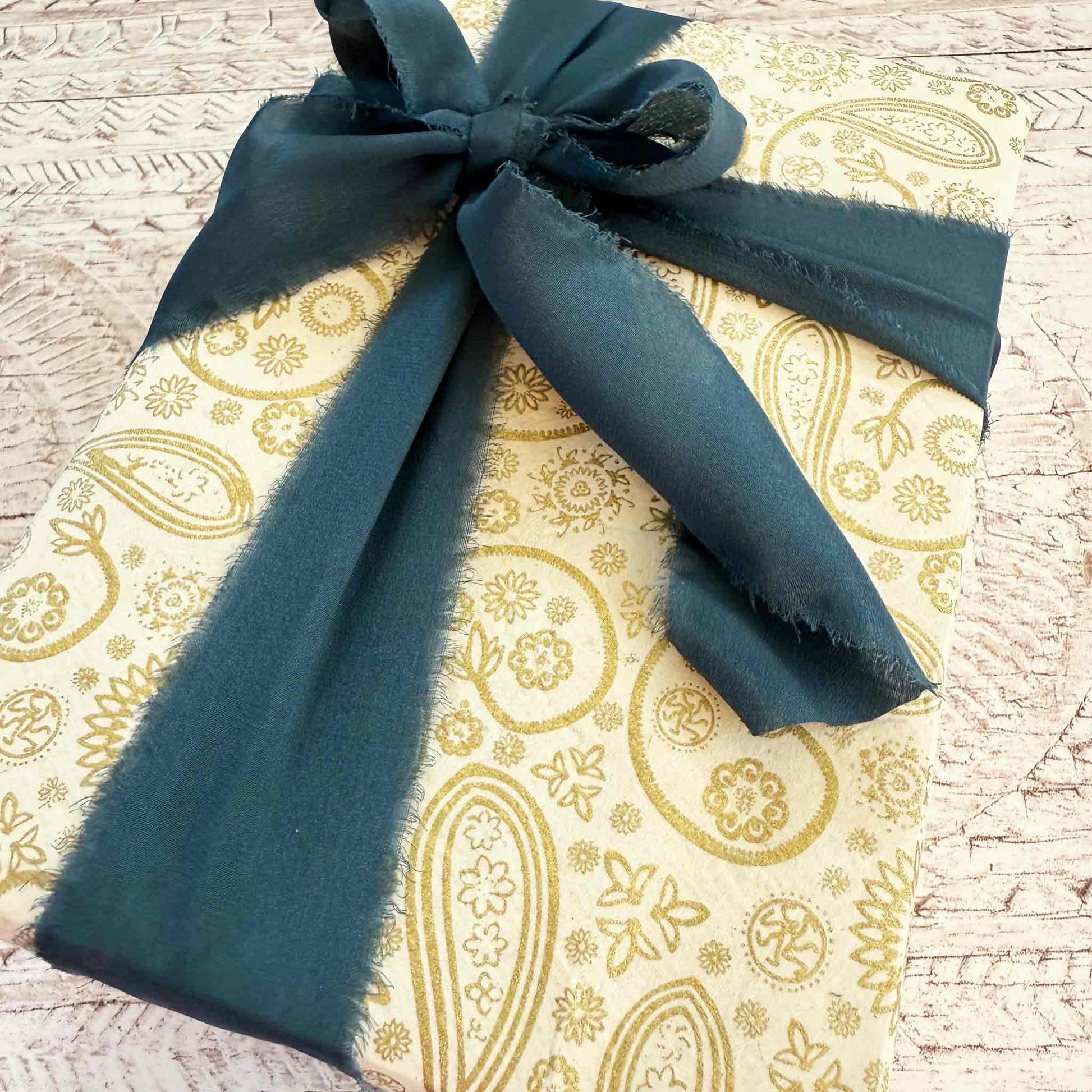 Gift wrapped in gold patterned paper with a blue silk ribbon 