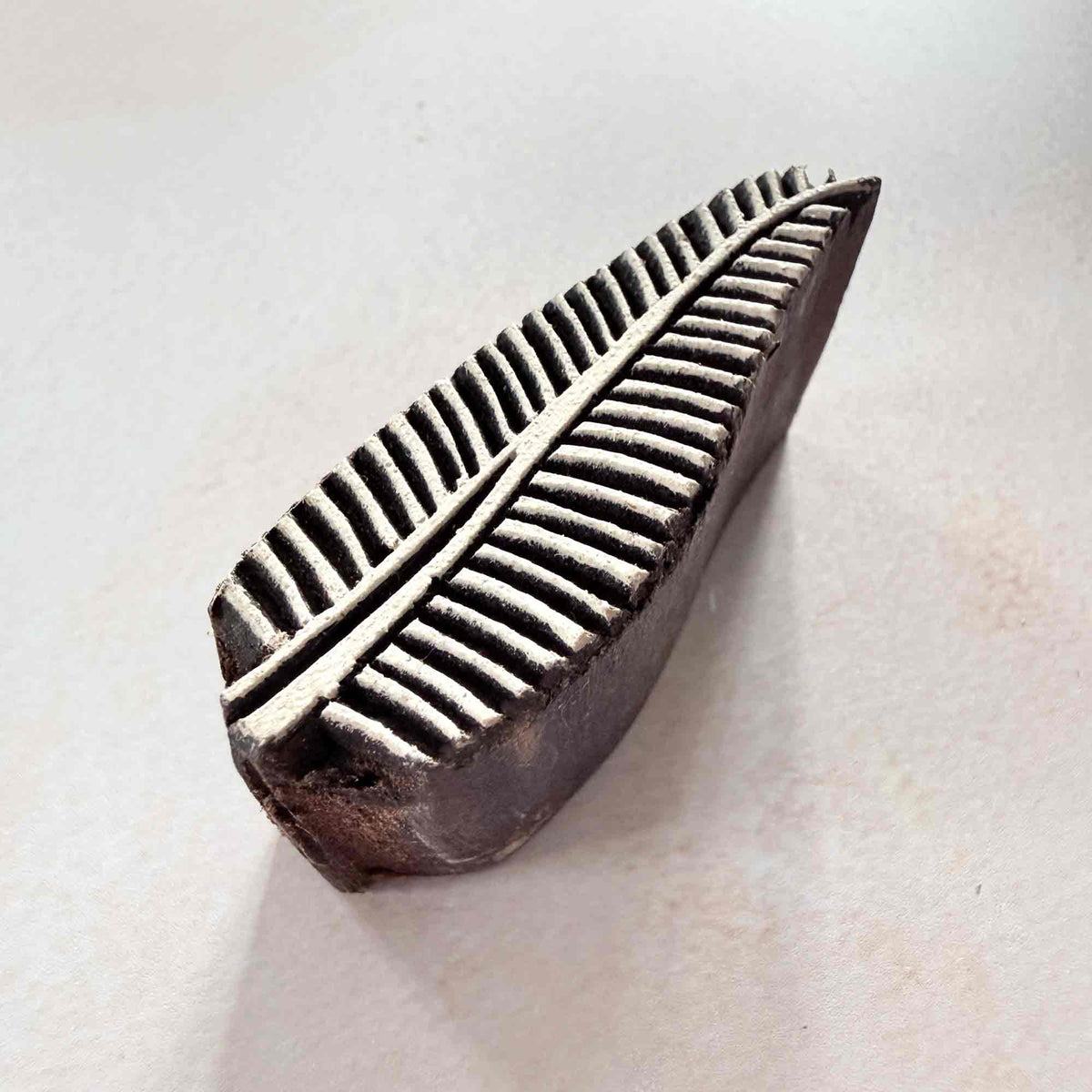Hand-carved Parna leaf wooden stamp with central vein and fine linear pattern