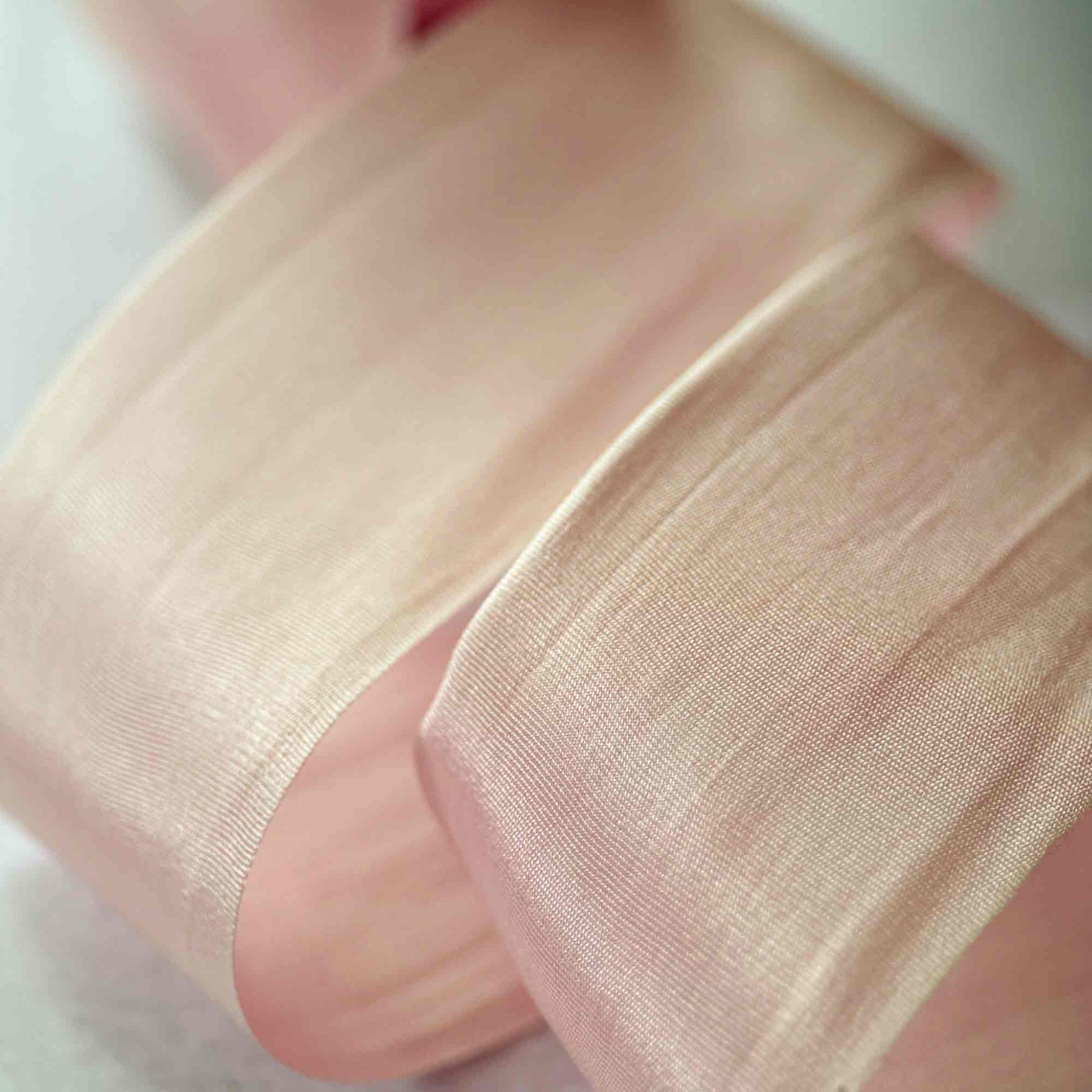 Close-up of a hand wearing sheer beige fabric over a white background