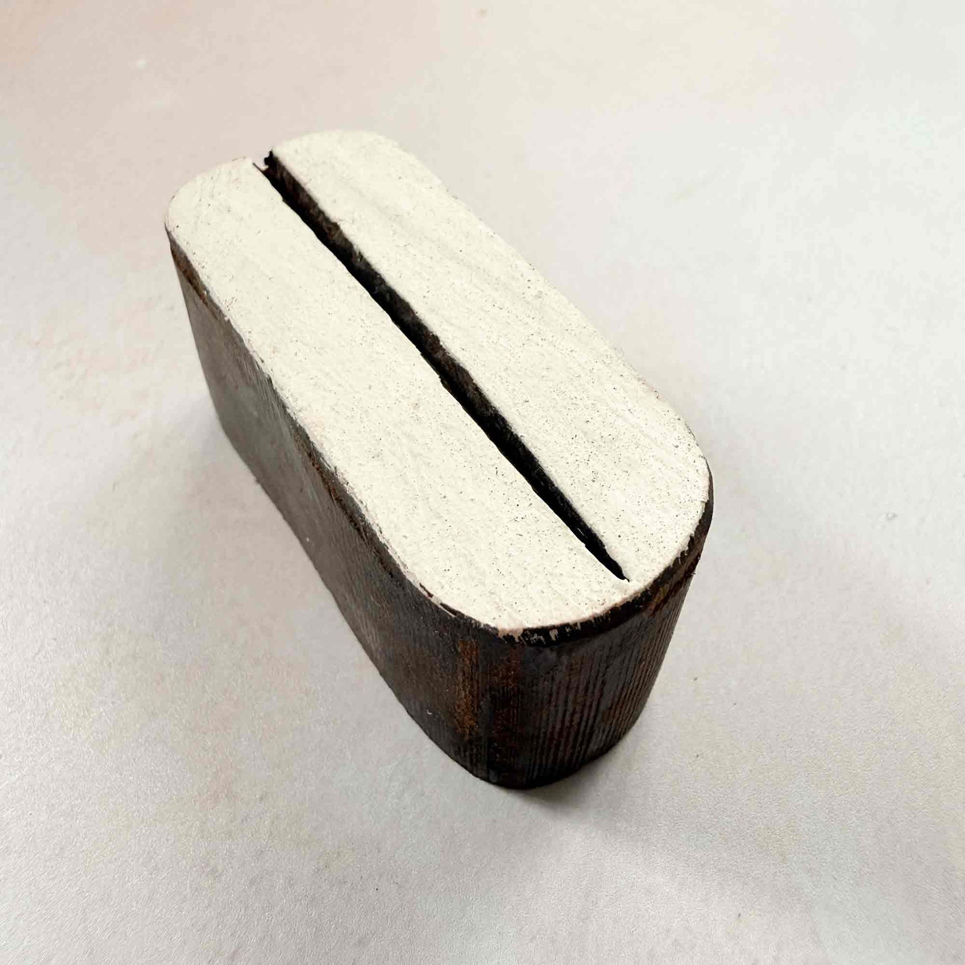 Hand-carved Pod Indian wood block stamp — elegant split-oval shape viewed from a gentle angle, showing smooth curved form and carved depth, traditional hardwood printing block