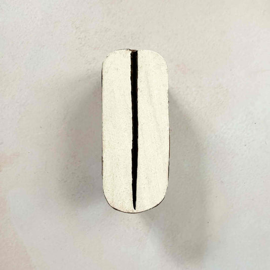 Pod wooden stamp — sleek split-oval design face-on view on soft pale background, single central slit through rounded organic shape, handcrafted Indian printing block