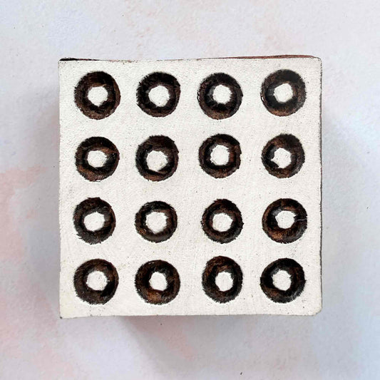 Hand-carved Polkas Indian wood block stamp — square grid of outlined ring dots face-on view on soft pale background, traditional dotted printing block close-up