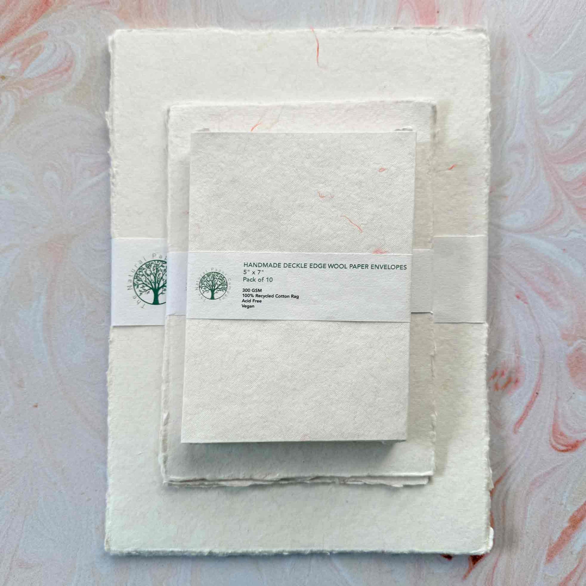 handmade paper with deckled edge and pink and yellow wool fibre decoration
