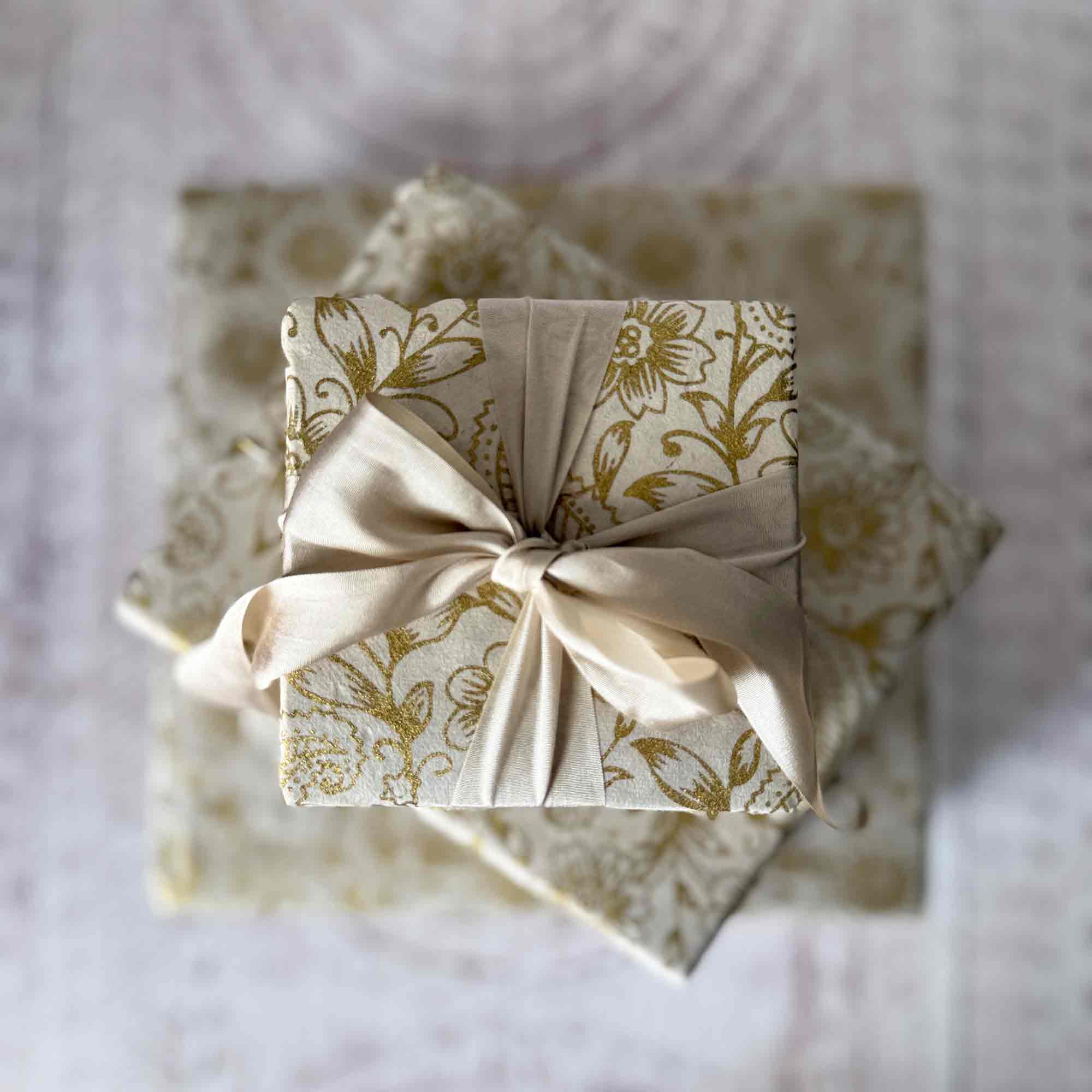 Top view of gift wrapped in Lokta paper with gold floral pattern and cream ribbon bow
