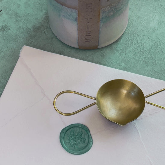 Make wax seals with a two handle melting spoon, sealing wax beads and a candle