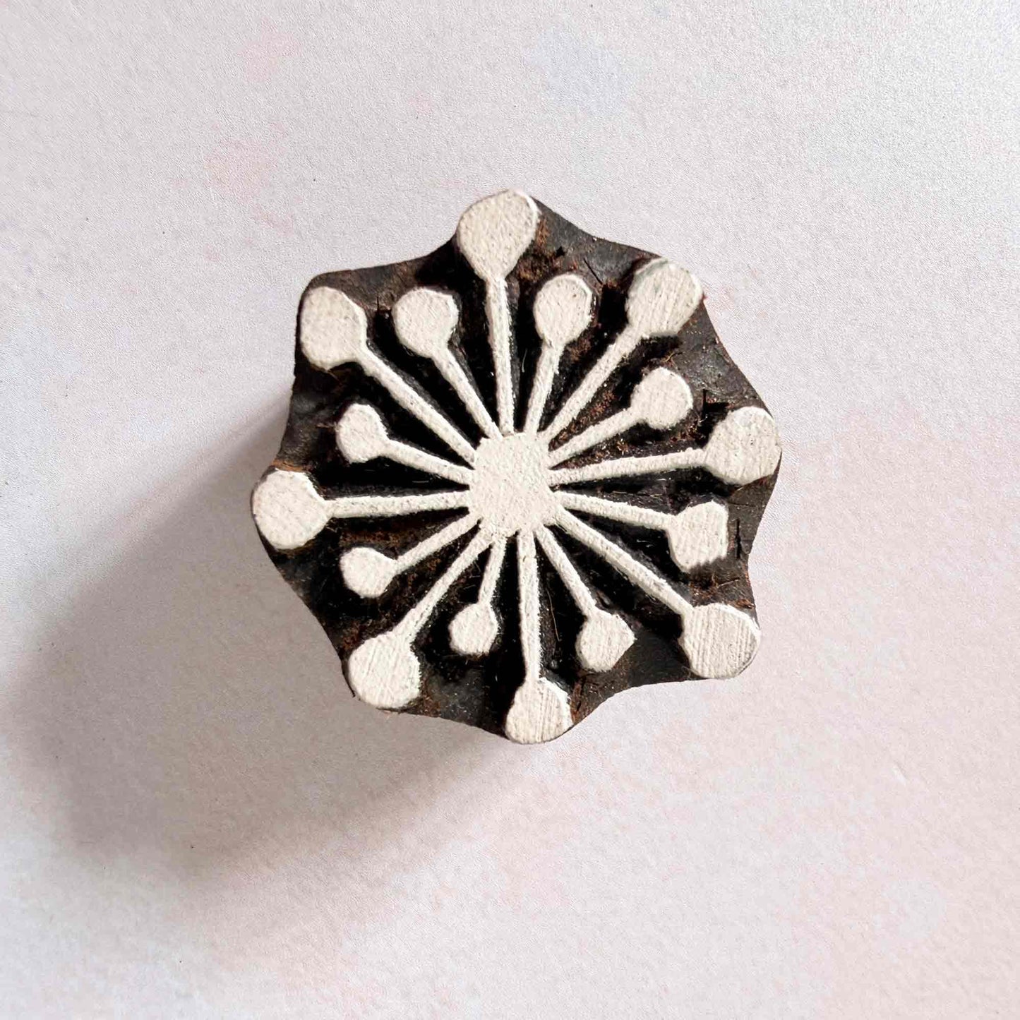 Hand-carved Radiance Indian wood block stamp — fourteen rounded rays sunburst face-on view on soft pale background, symmetrical ray motif traditional printing block from India