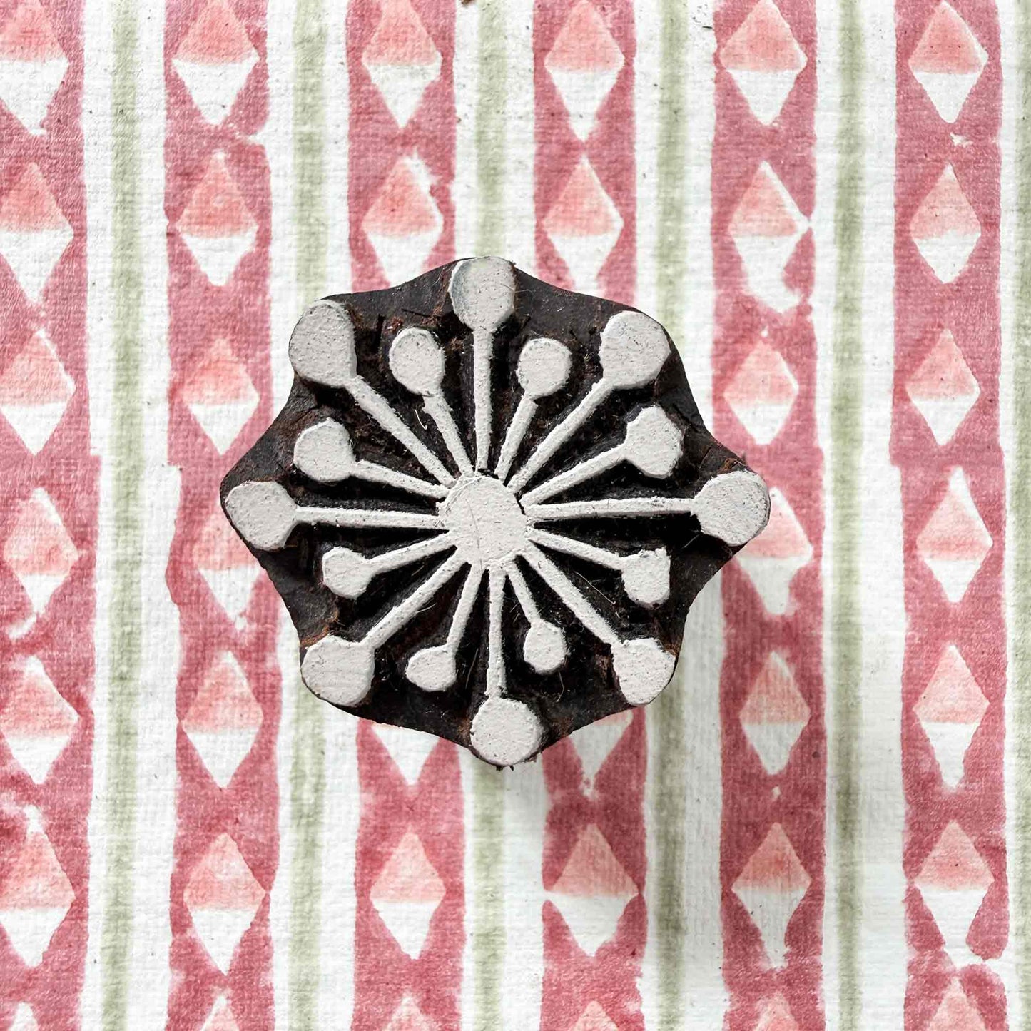 Radiance wooden stamp — delightful sunburst design resting on block printed fabric, rays radiating from central circle, handcrafted Indian printing block ready for printing
