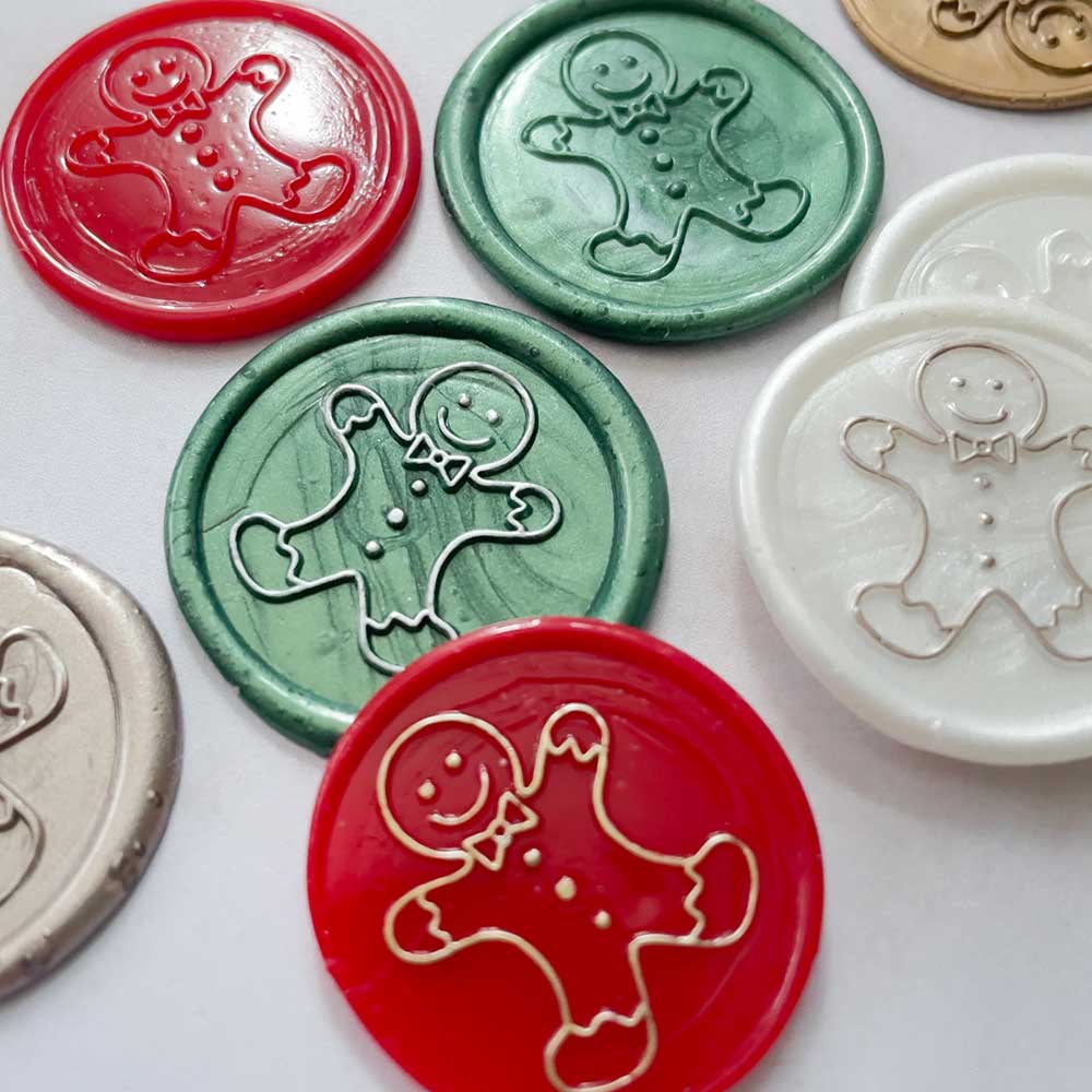 Seasonal wax seal stamps in red, green, white and gold with metallic details.  Gingerbread Man wax stamp by By The Natural Paper Company