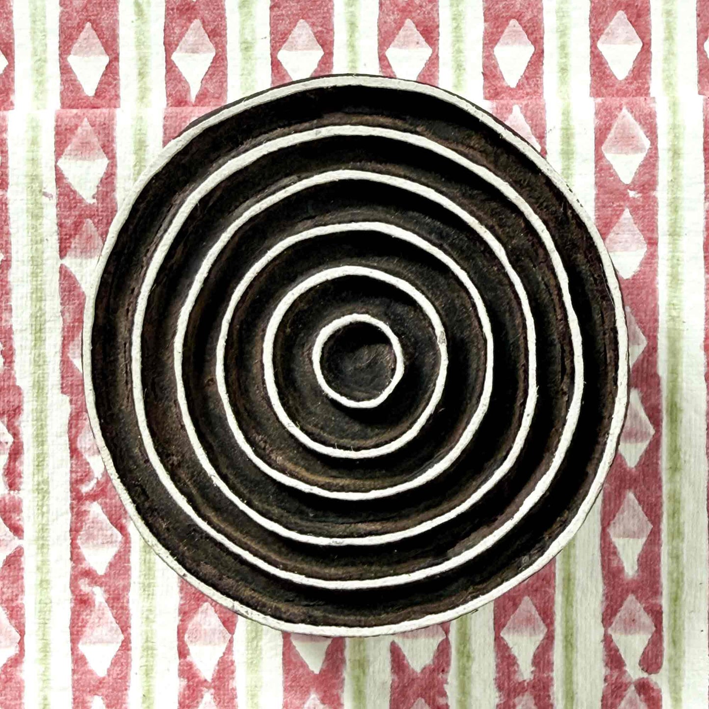 Indian wood block stamp — Ripple concentric rings resting on block printed fabric, seven evenly spaced flowing bands, hand-carved wooden stamp, classic traditional printing block ready for printing