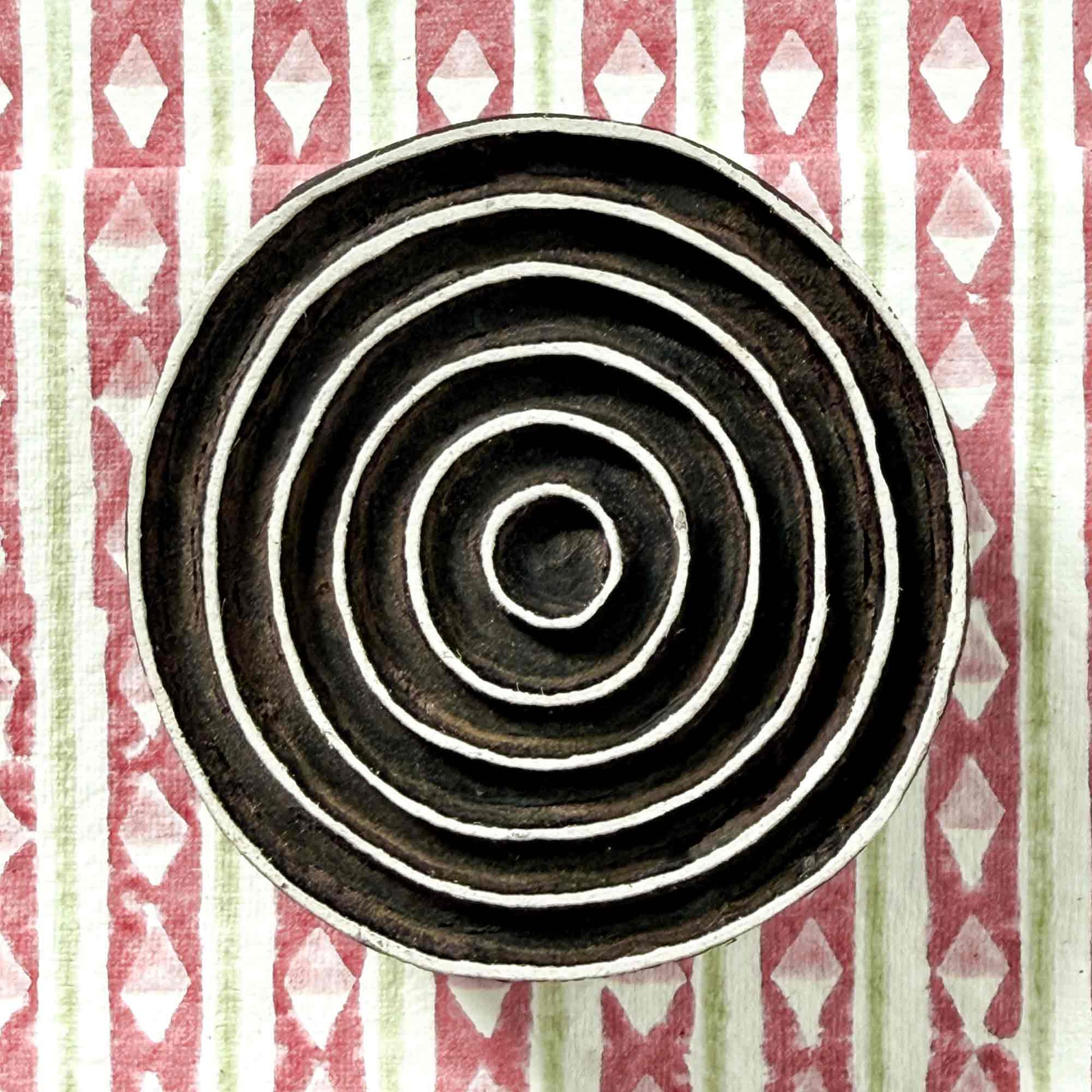 Indian wood block stamp — Ripple concentric rings resting on block printed fabric, seven evenly spaced flowing bands, hand-carved wooden stamp, classic traditional printing block ready for printing