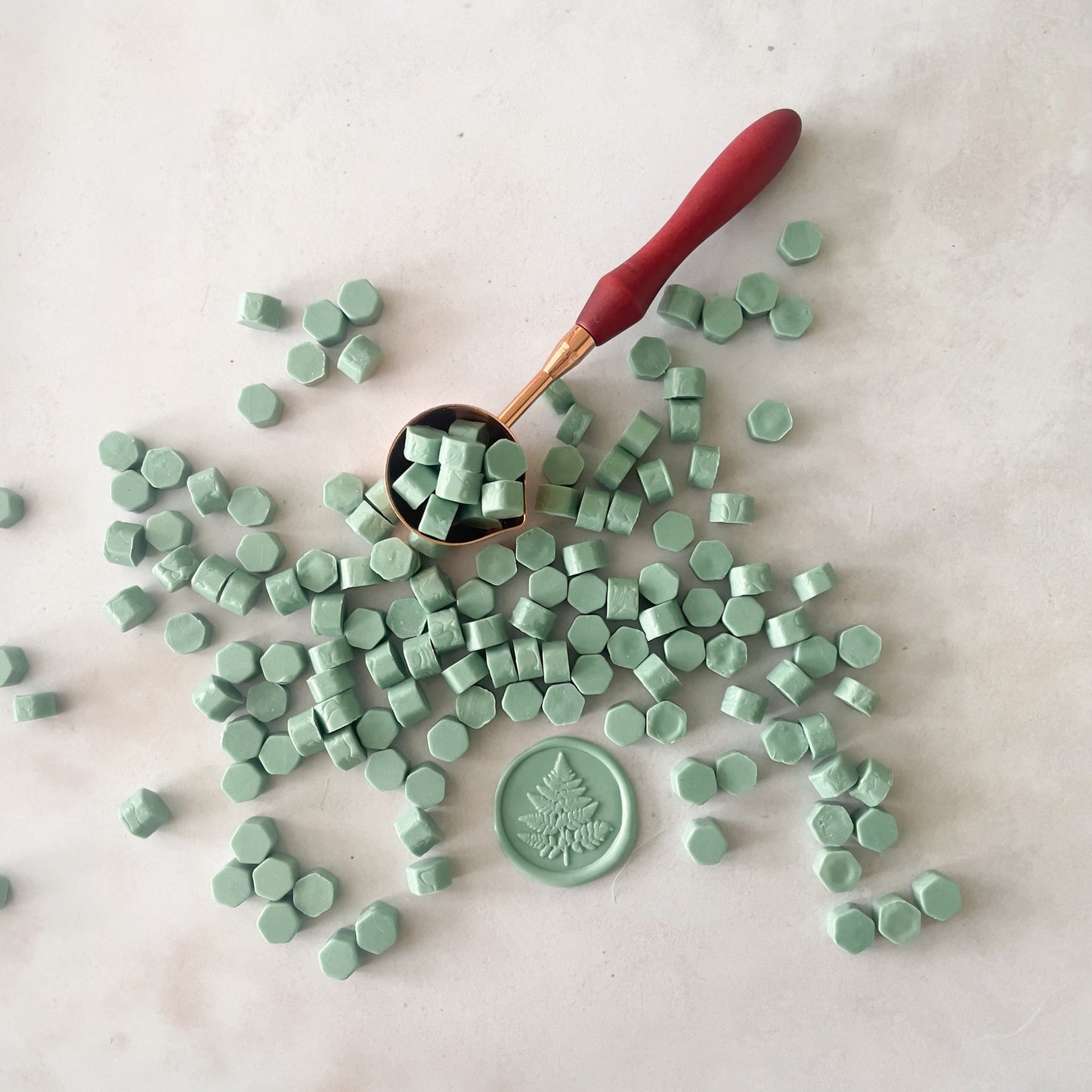 Small beads of sage green wax to make wax seals.  Eco friendly sealing wax by The Natural Paper Company