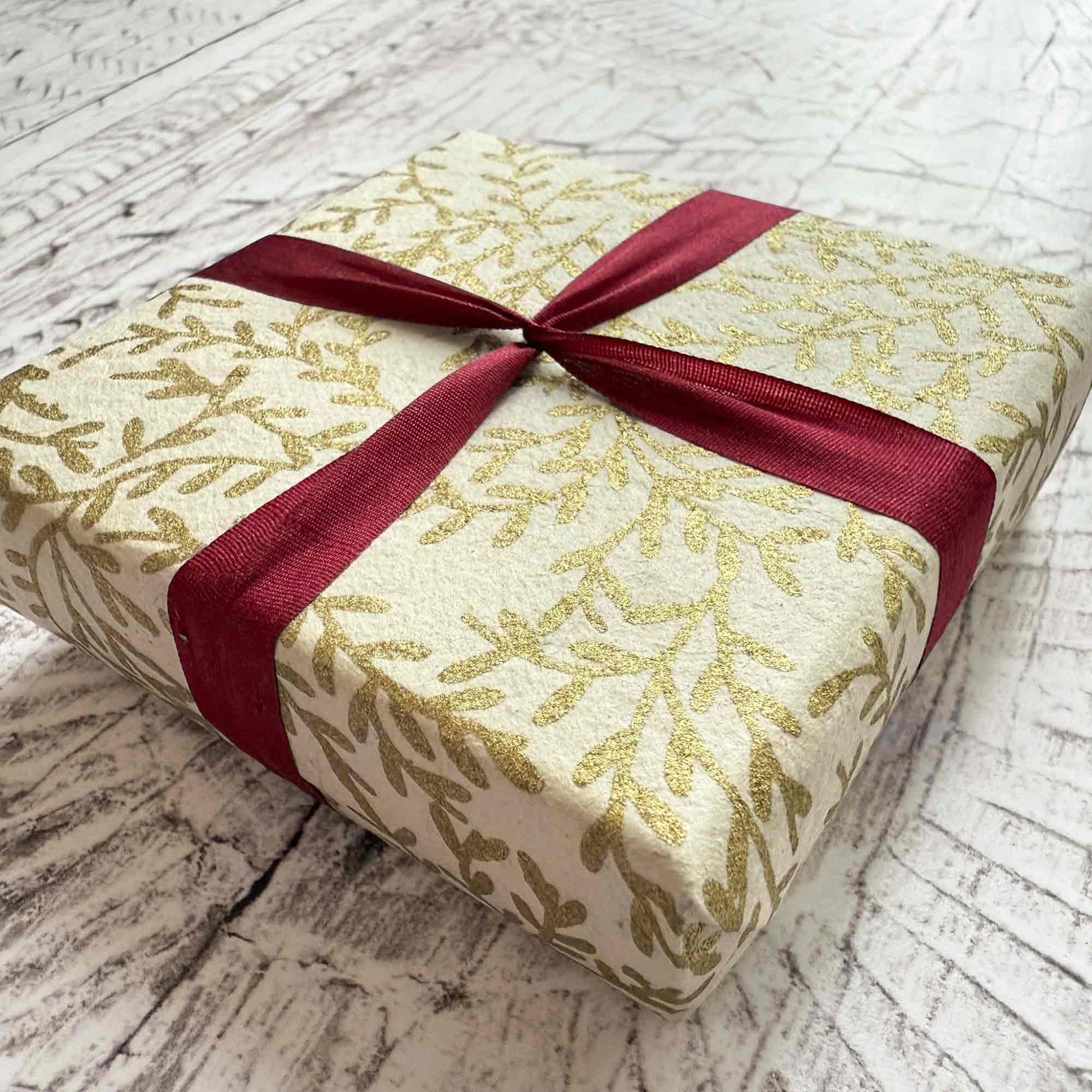 small gift wrapped in gold and white lokta paper