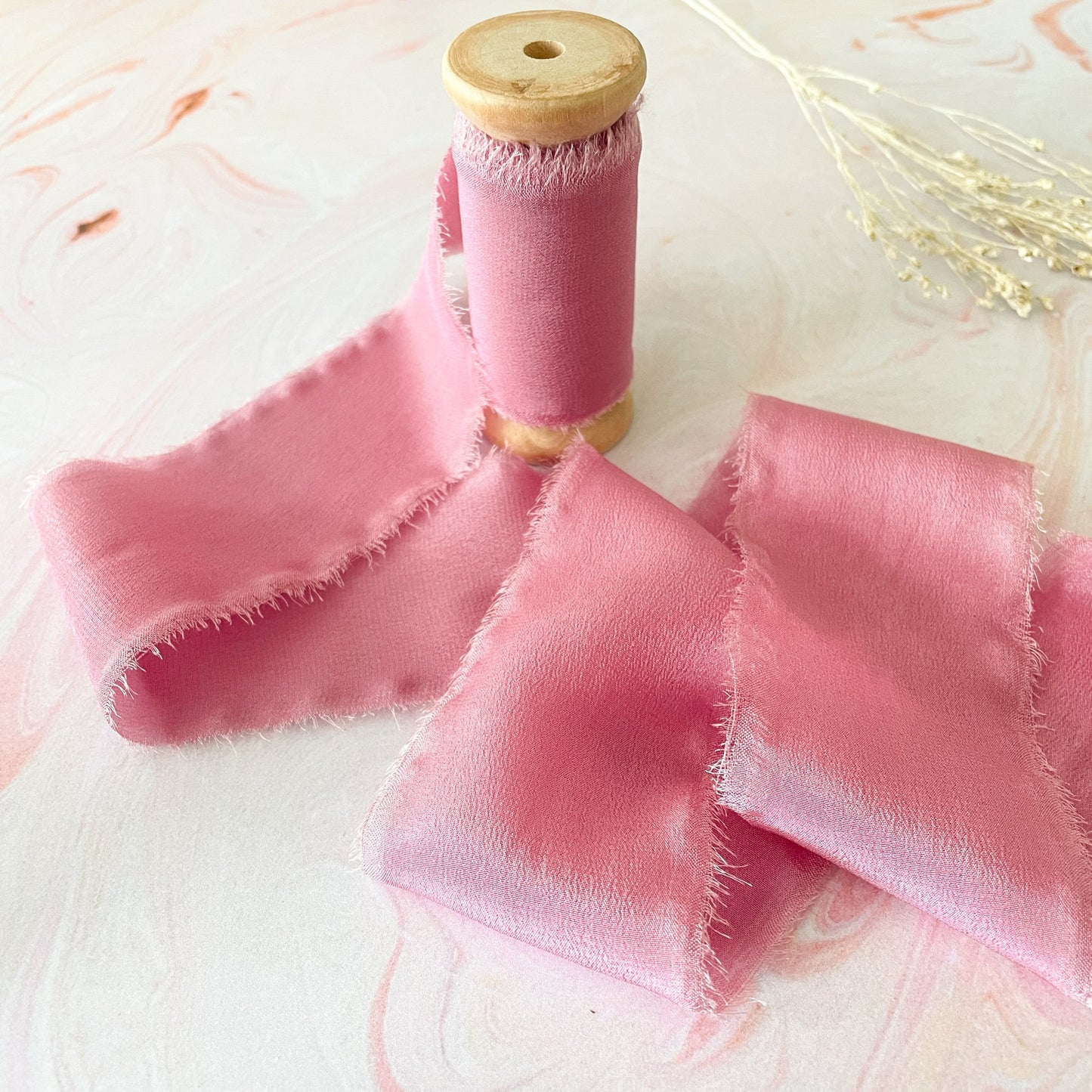 Soft raspberry pink silk ribbon By The Natural Paper Company.  Luxury silk ribbon with frayed edges.  By The Natural Paper Company.