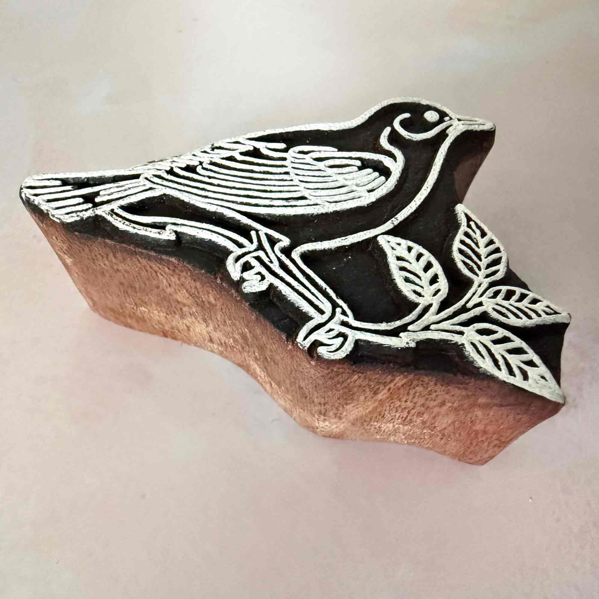 A wood block stamp with a bird standing on a branch.  