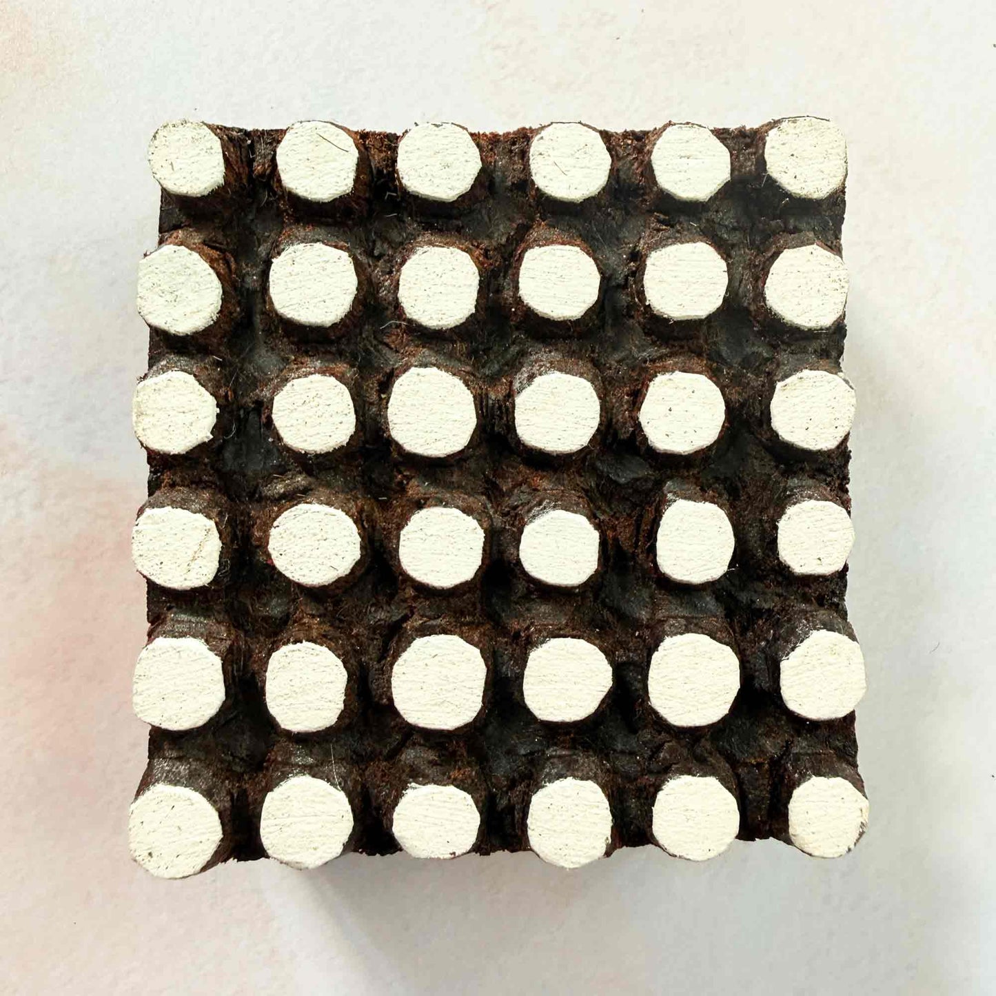 Spotty wooden stamp — dotted grid design viewed from side on pale background, handcrafted Indian printing block with raised rounded dots
