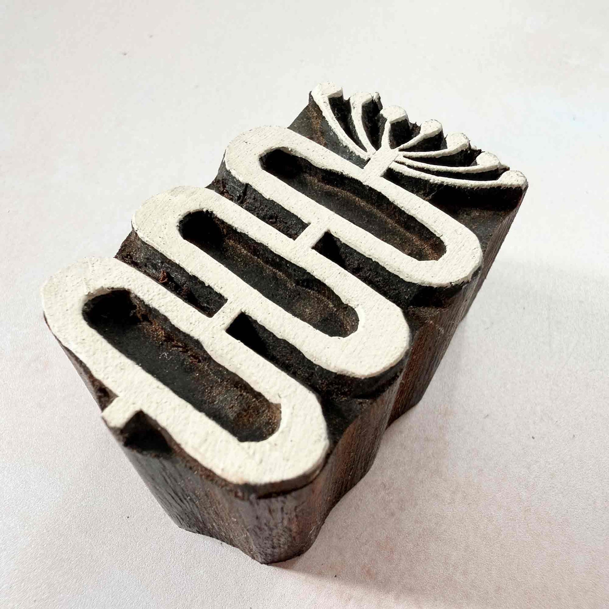 Stem Indian wood block stamp — graceful botanical design viewed from side, showing carved depth and smooth curved form, handcrafted hardwood printing block on neutral background