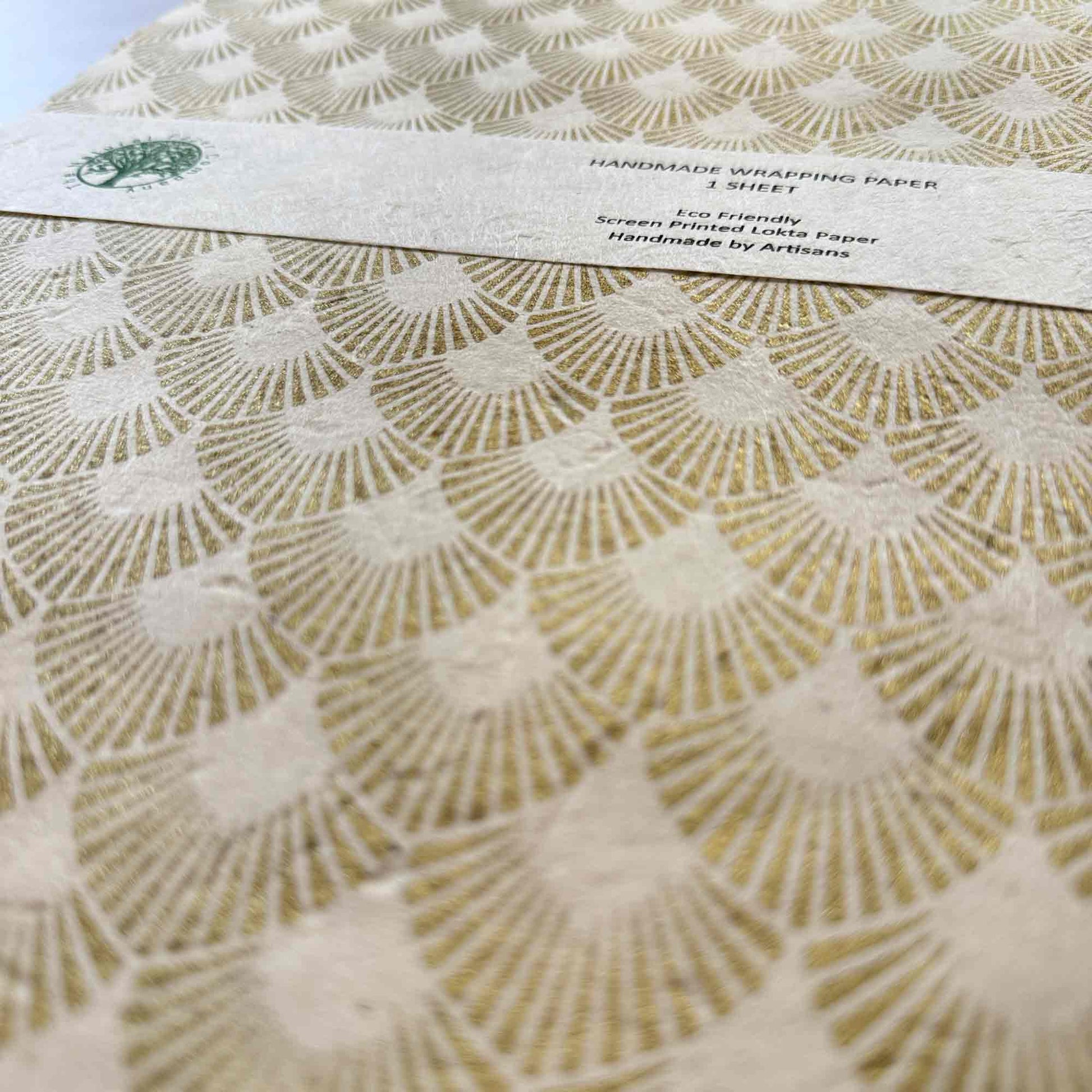 Textured Lokta paper wrapping paper close-up, hand screen printed gold metallic pattern, sustainable artisan gift wrap