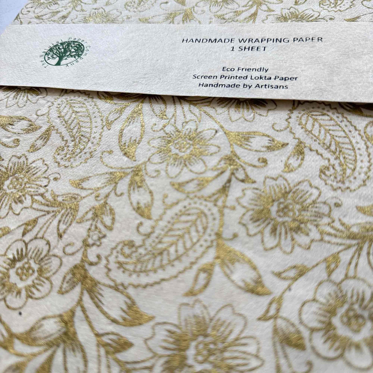 Close-up of hand screen printed gold floral and paisley design on natural textured Lokta paper

