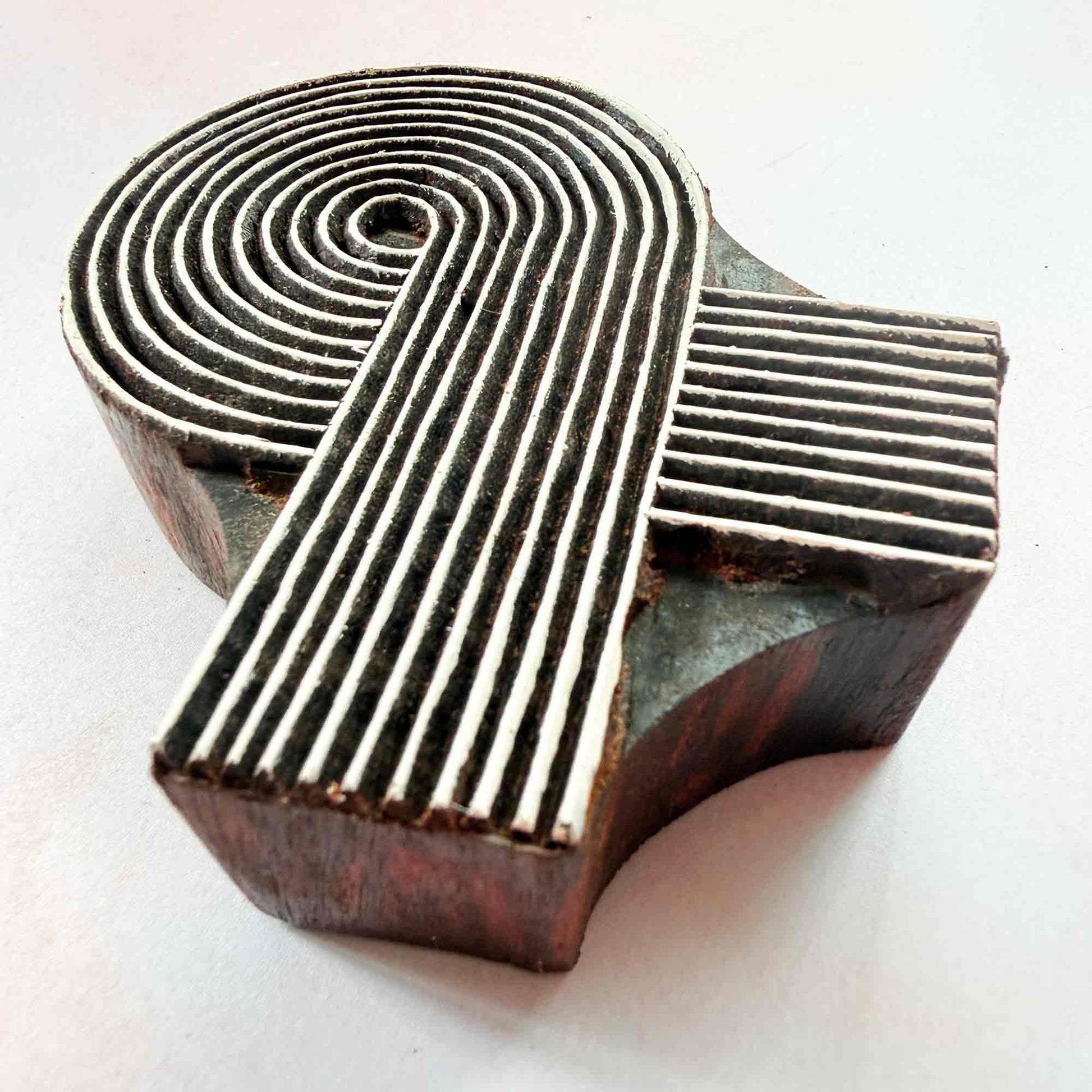Swirl wooden stamp — spiral ribbon motif viewed from side on soft pale background, handcrafted Indian printing block with fine lined curves