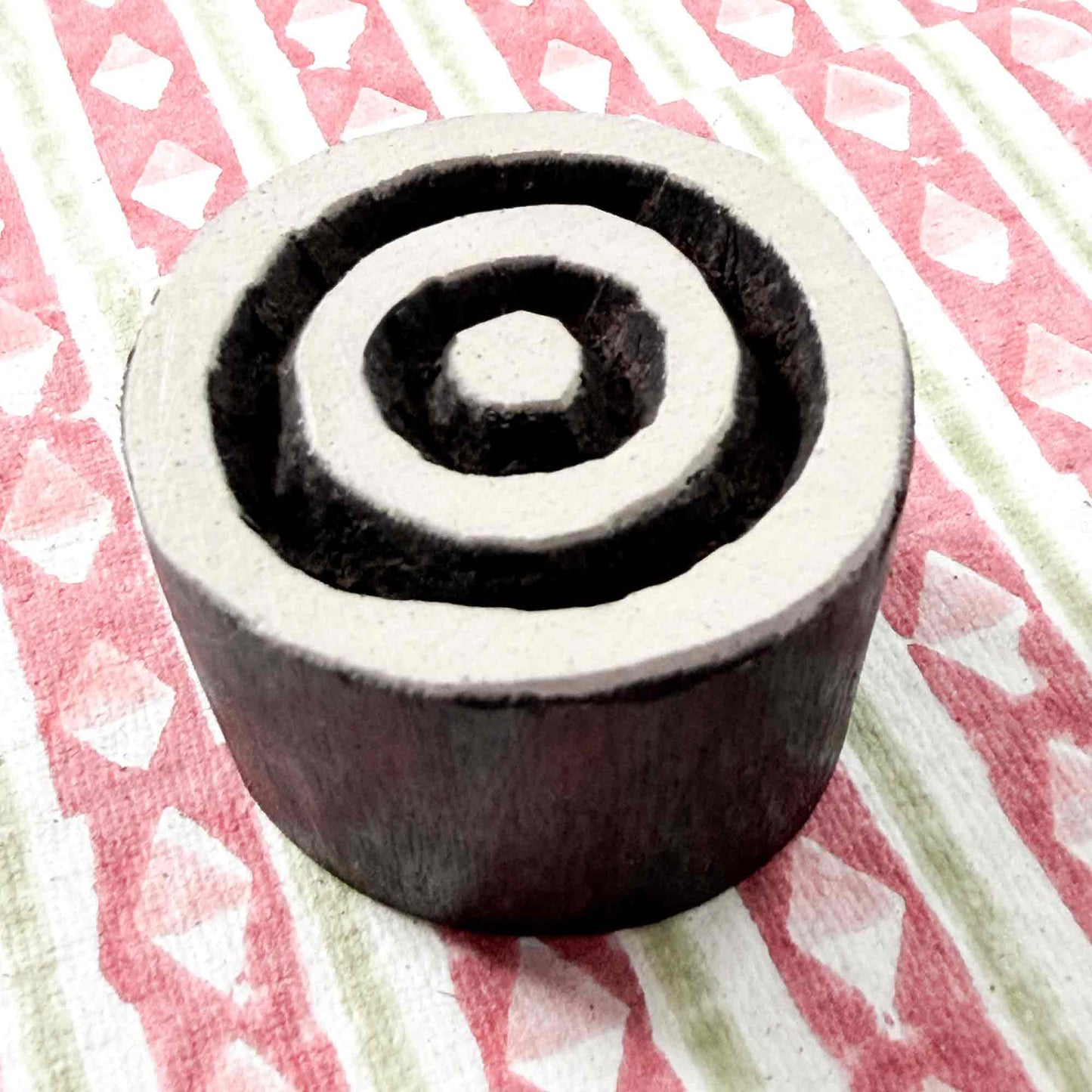Indian wood block stamp — Target concentric circles resting on block printed fabric, central dot and three even rings, hand-carved wooden stamp, classic traditional printing block ready for printing