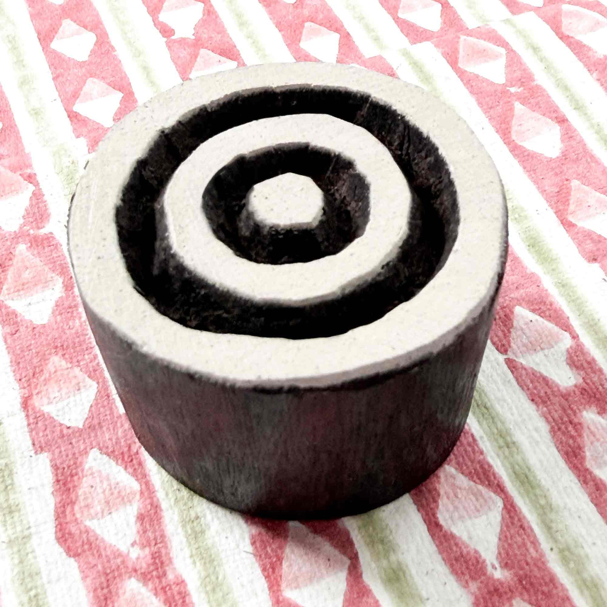 Indian wood block stamp — Target concentric circles resting on block printed fabric, central dot and three even rings, hand-carved wooden stamp, classic traditional printing block ready for printing