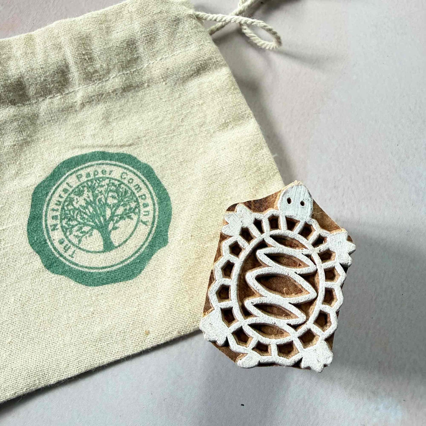 turtle pattern wooden stamp next to branded gift bag by The Natural Paper Company