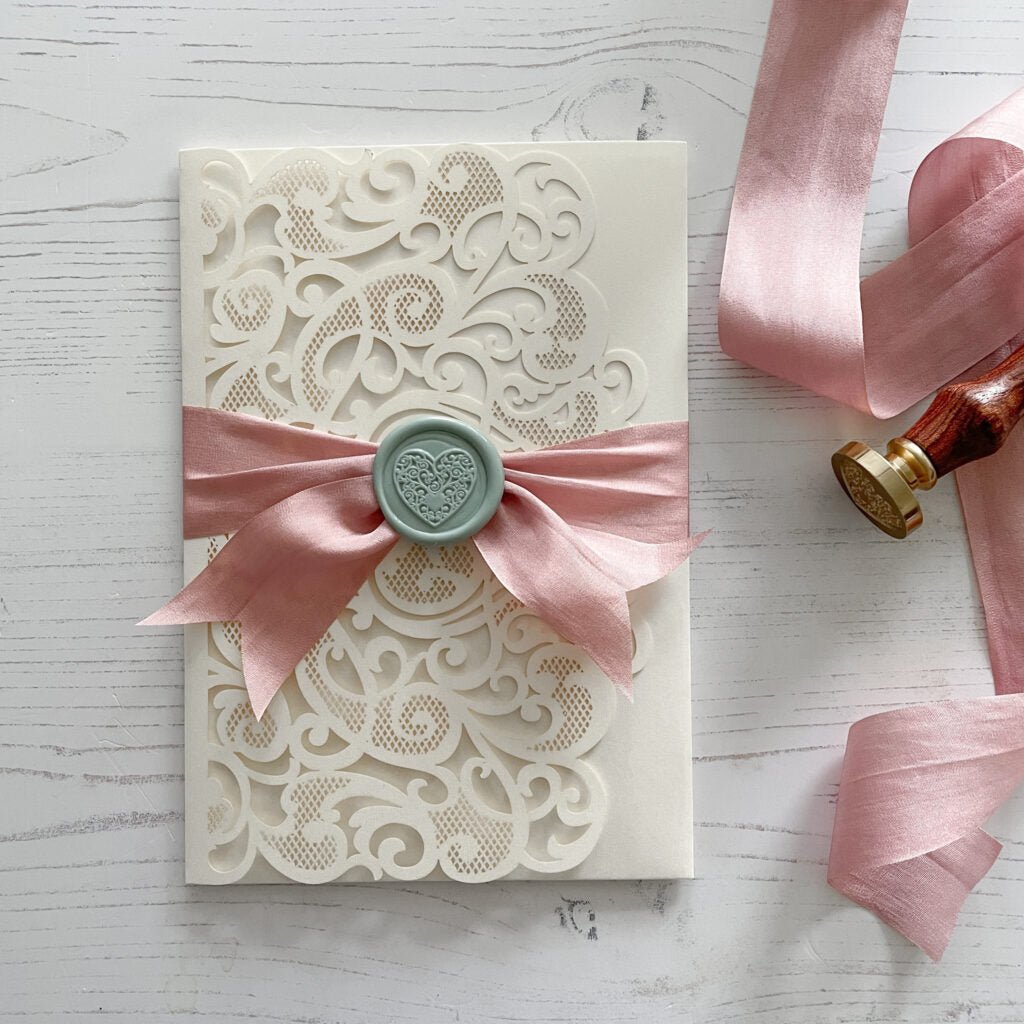 Lace wedding invitation with silk ribbon and wax seal.  Made with dusky pink silk ribbon and sage green wax seal with a heart design.  By The Natural Paper Company