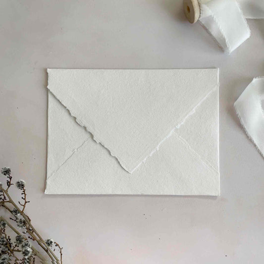 White Handmade paper envelope with deckled edges and a pointed flat.  Cotton Rag invitation envelopes by The Natural Paper Company