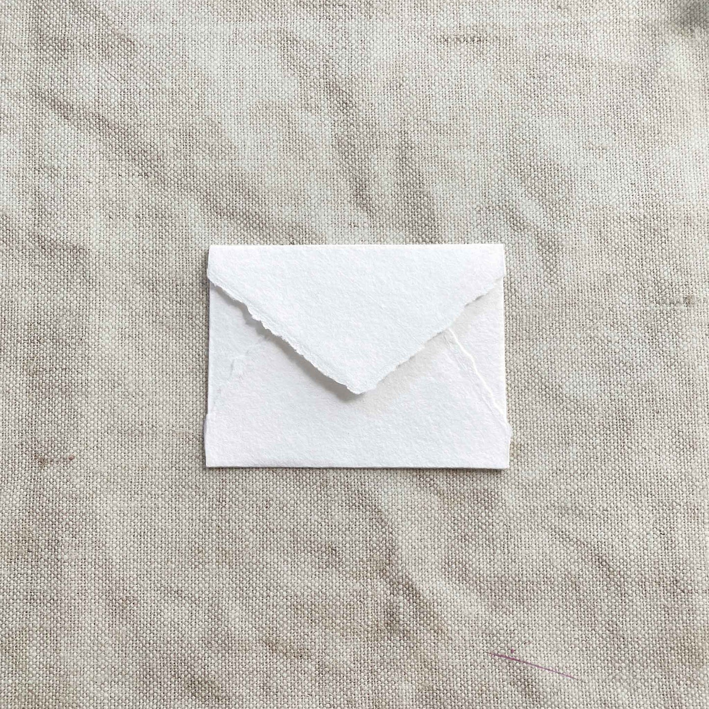 Small rsvp envelope made from white handmade cotton rag paper with deckled edges