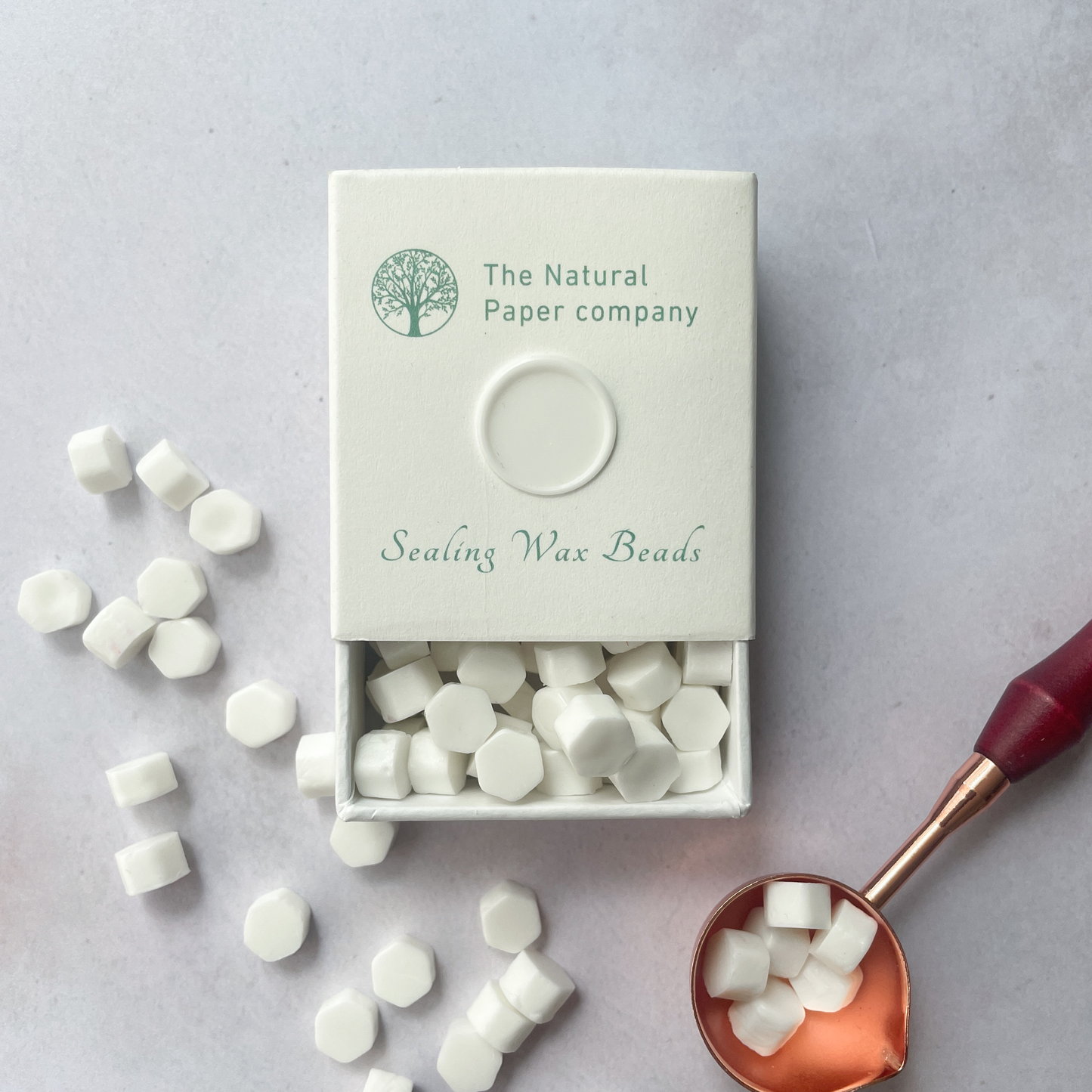 White sealing wax beads in a box.  Small beads of wax to make wax seals with a melting spoon.  Eco friendly.  The Natural paper Company