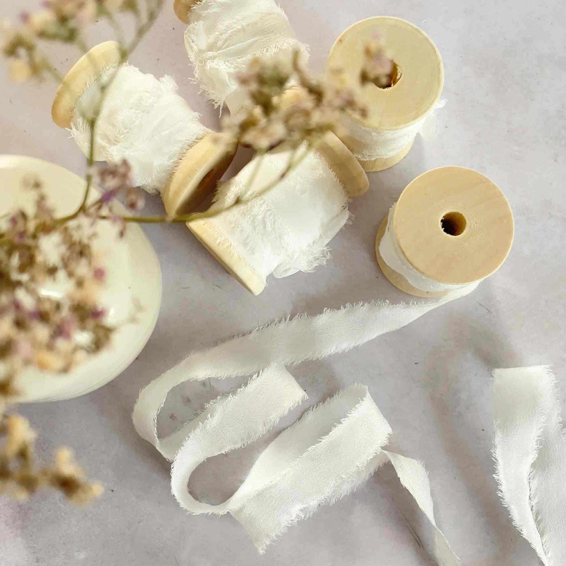 narrow silk ribbon in white.  Habotai silk ribbon on a wooden reel