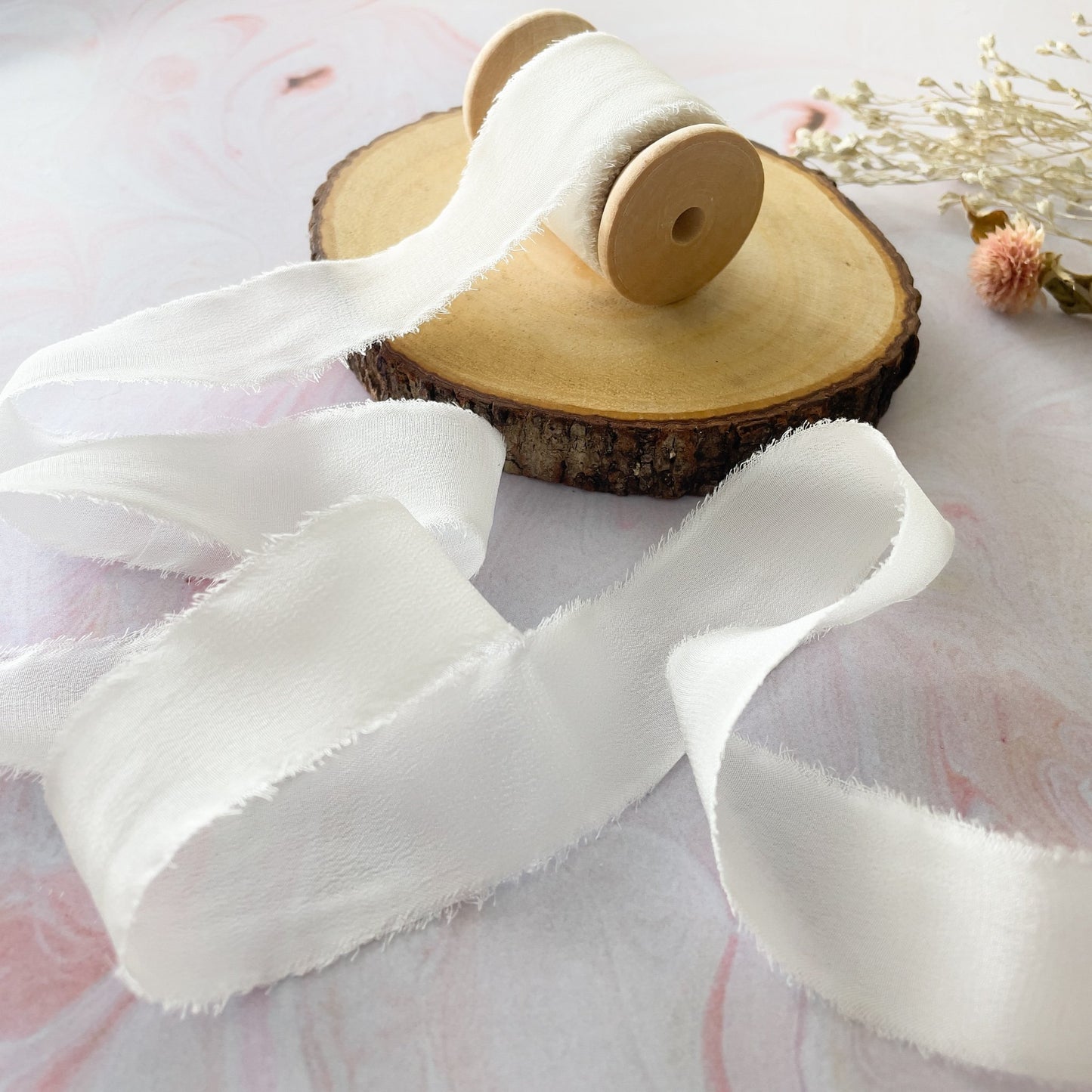 White silk ribbon with a raw edge.  Delicate silk ribbon for crafts.  Sold on a wooden reel.  By The Natural Paper Company