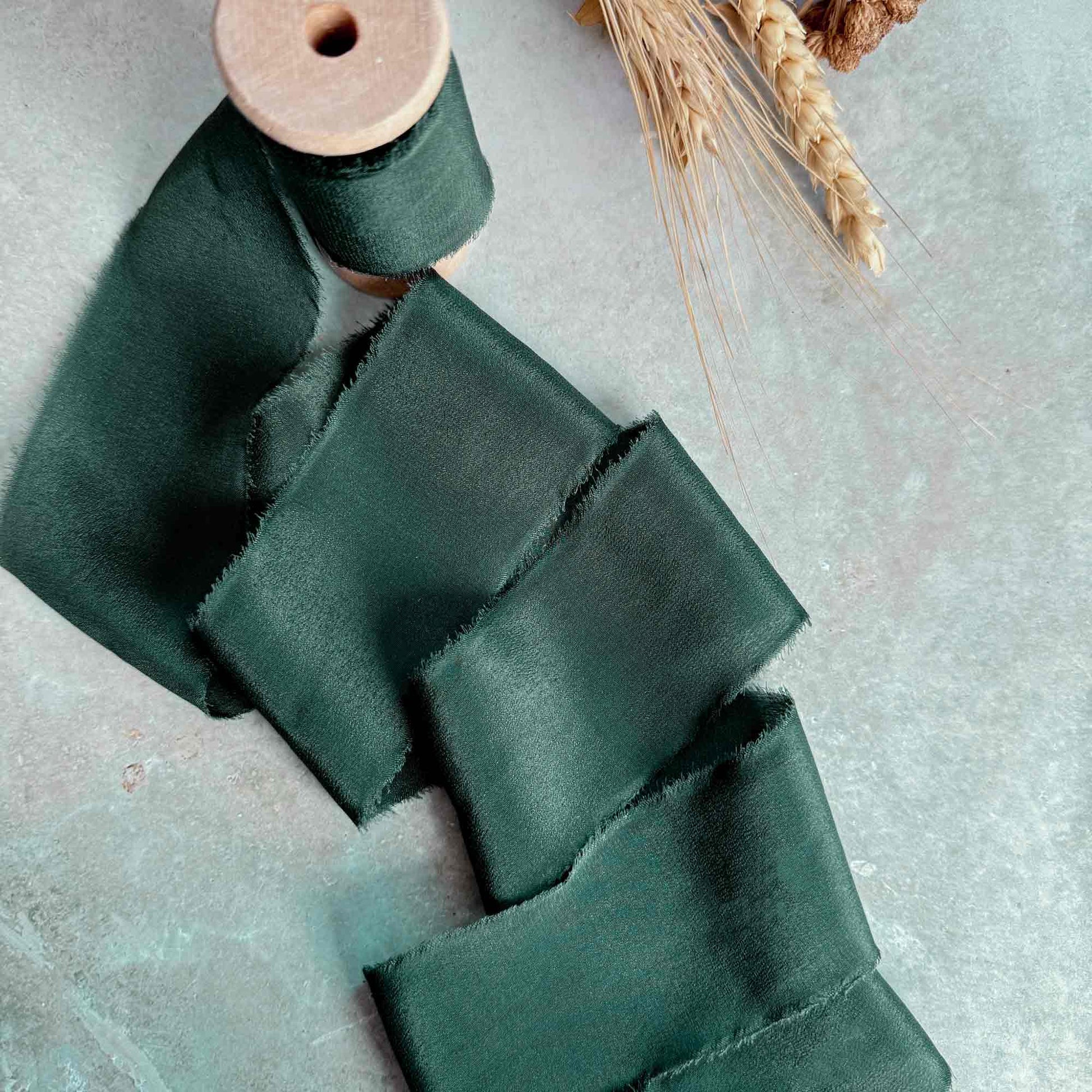 dark green frayed edge ribbon on a wooden reel