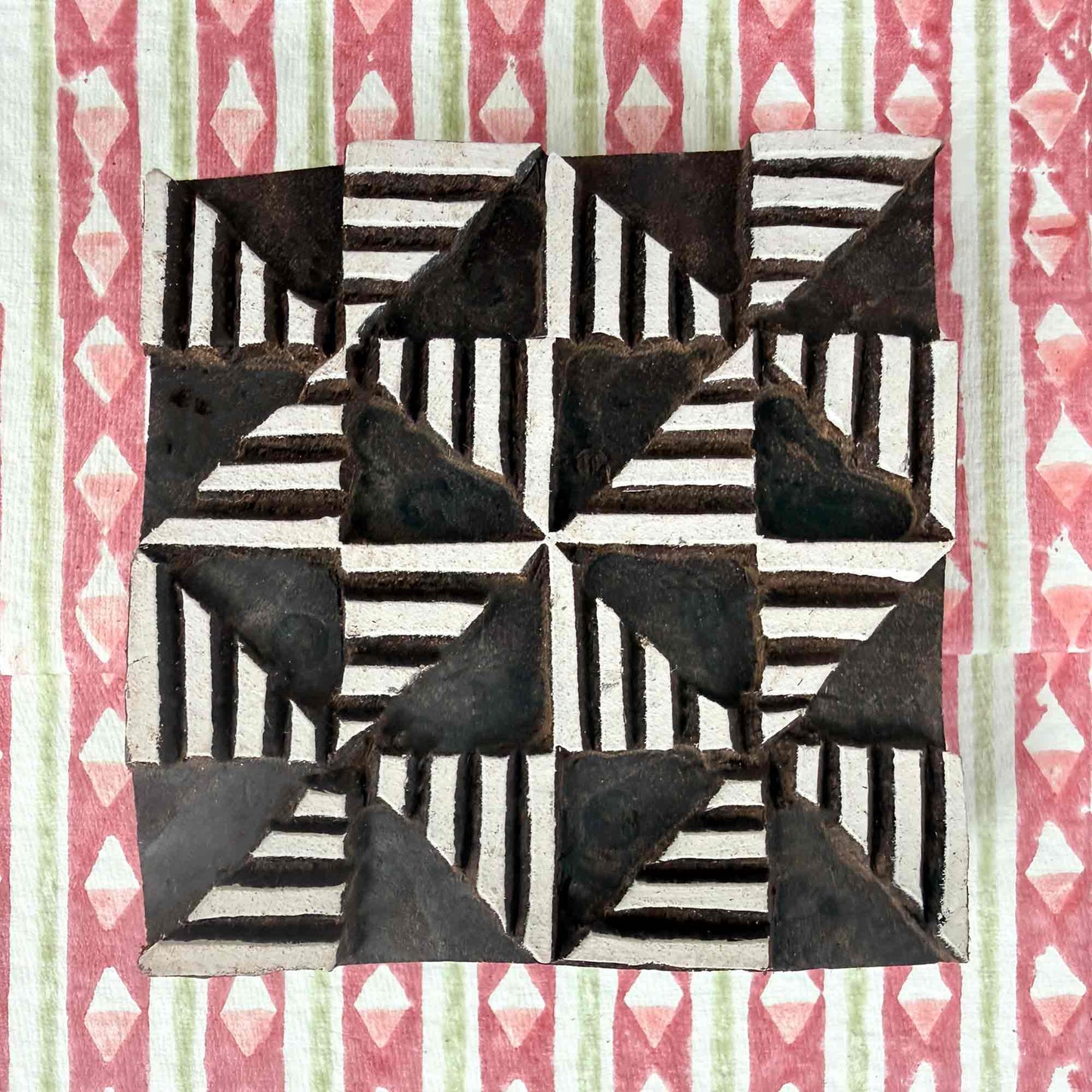 Windmill Indian wood block stamp resting on block printed fabric — lively radiating geometric motif ready for printing, authentic artisan hand-carved block