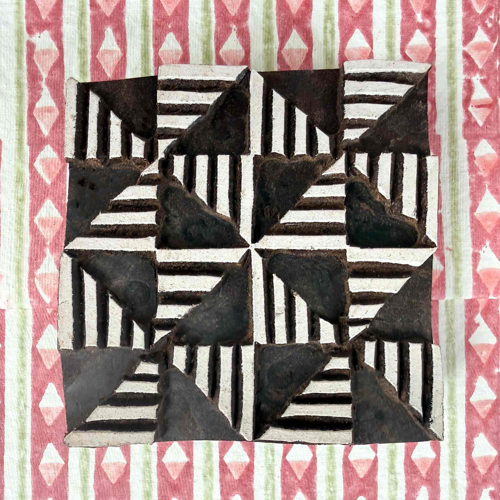 Windmill Indian wood block stamp resting on block printed fabric — lively radiating geometric motif ready for printing, authentic artisan hand-carved block