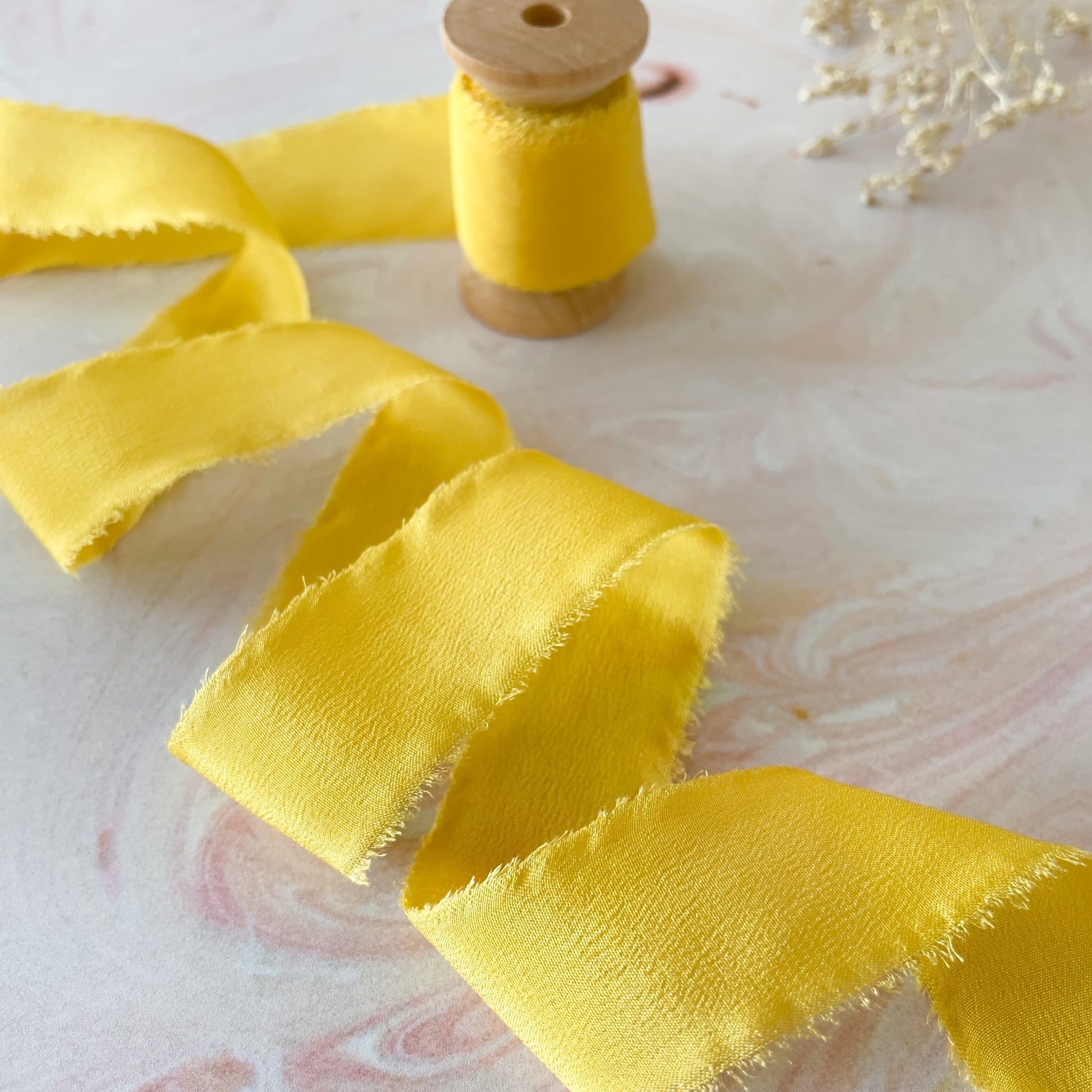 Bright yellow silk ribbon on a wooden reel.  Luxury habotai silk ribbon for decorating bridal flowers and wedding stationery.  By The Natural Paper Company.