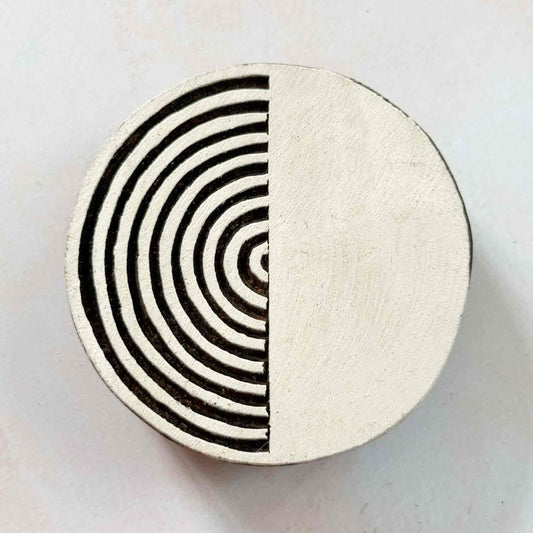 Indian wood block stamp — Yin split circle face-on view on pale background, half radiating arcs half solid, handcrafted wooden stamp, classic traditional printing block