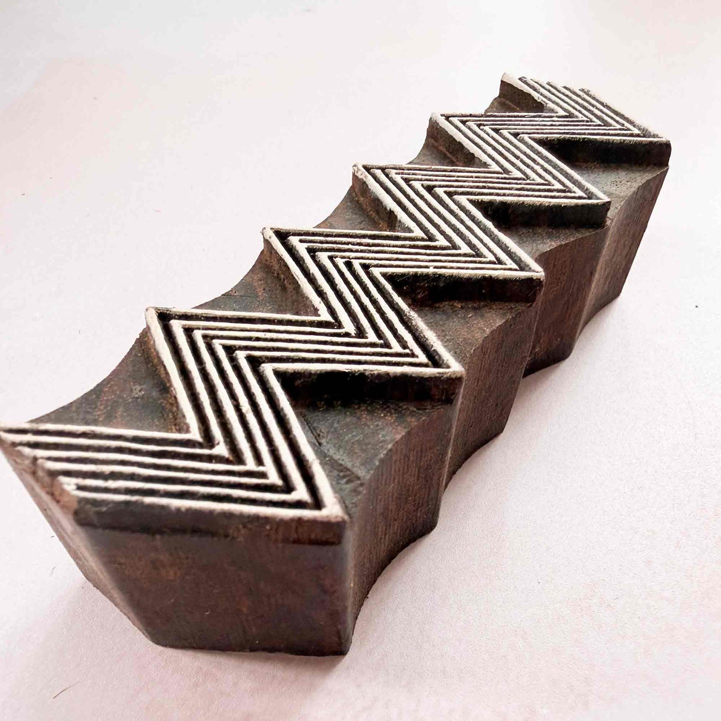 Hand-carved ZigZag Indian wood block stamp — lined chevron border viewed from angle, showing carved depth and stepped line texture, traditional hardwood printing block from India