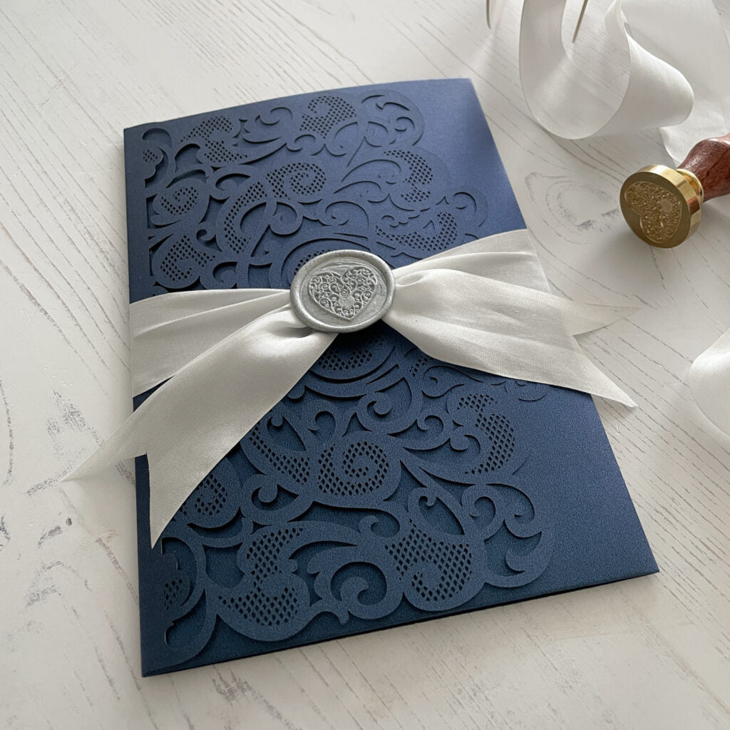 Pretty wedding invitation made using eco friendly materials.  Fine silk ribbon in white and eco friendly wax seal in silver.  Navy, white and silver invitation By The Natural Paper Company