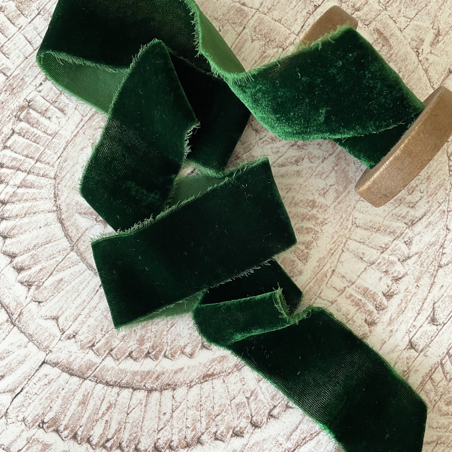 roll of dark green silk velvet ribbon with frayed edge.  Forest green luxury fine velvet ribbon 